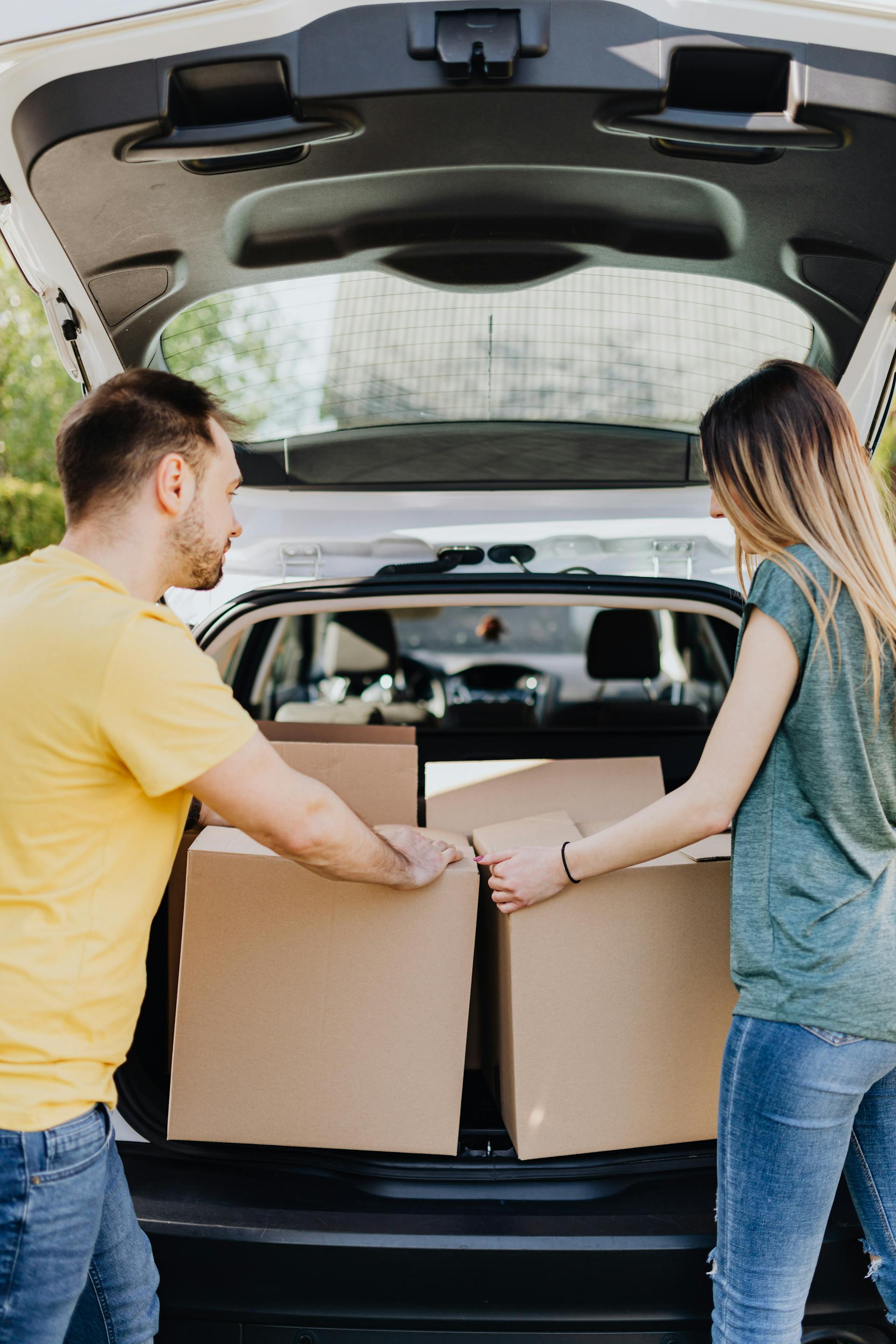 Un couple sortant des boîtes en carton du coffre d'une voiture | Source : Pexels