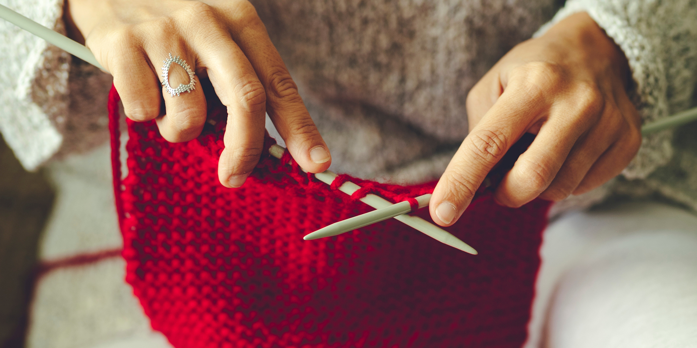 Une femme tricotant un pull rouge | Source : Shutterstock