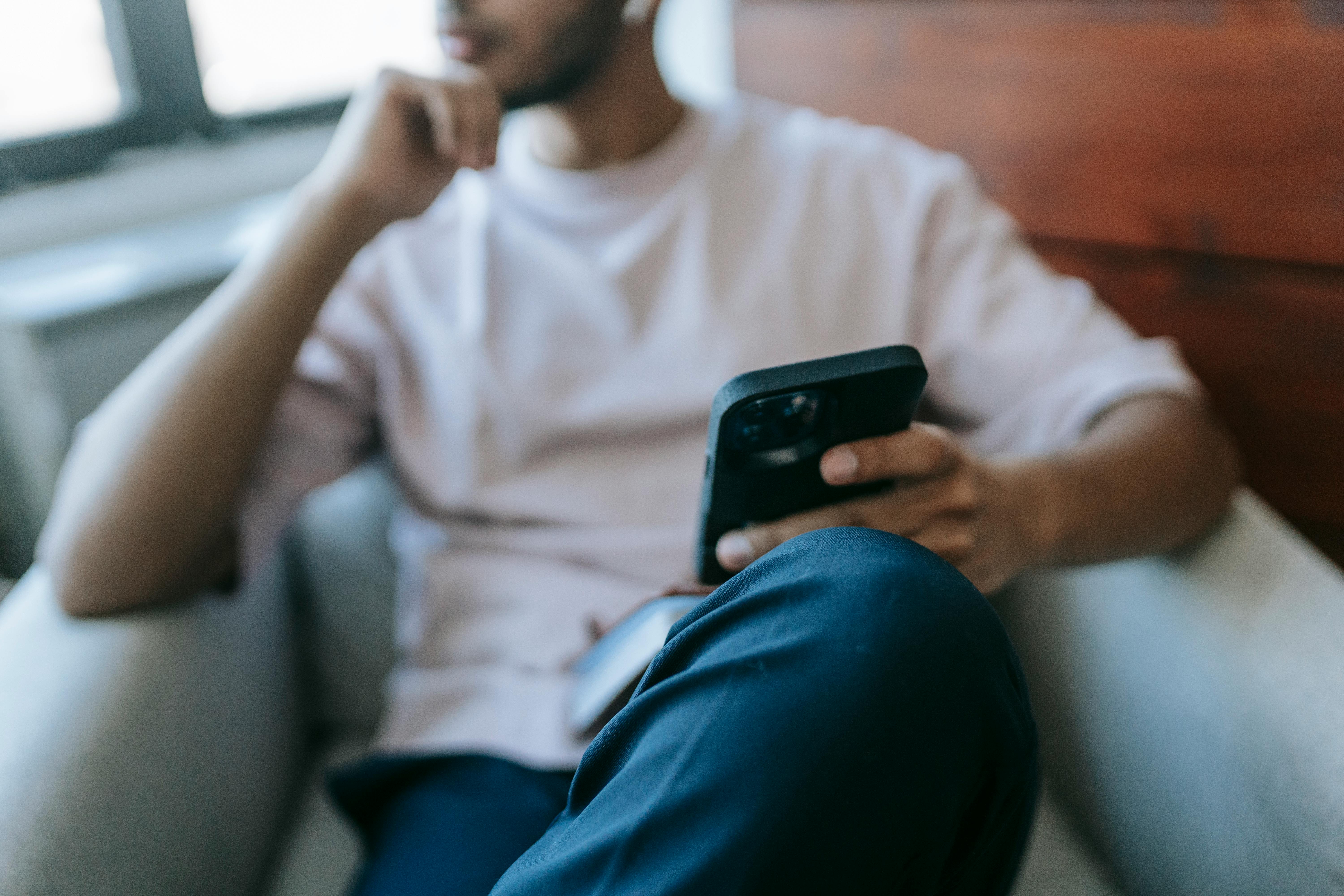 Un homme plongé dans ses pensées tout en tenant son téléphone | Source : Pexels