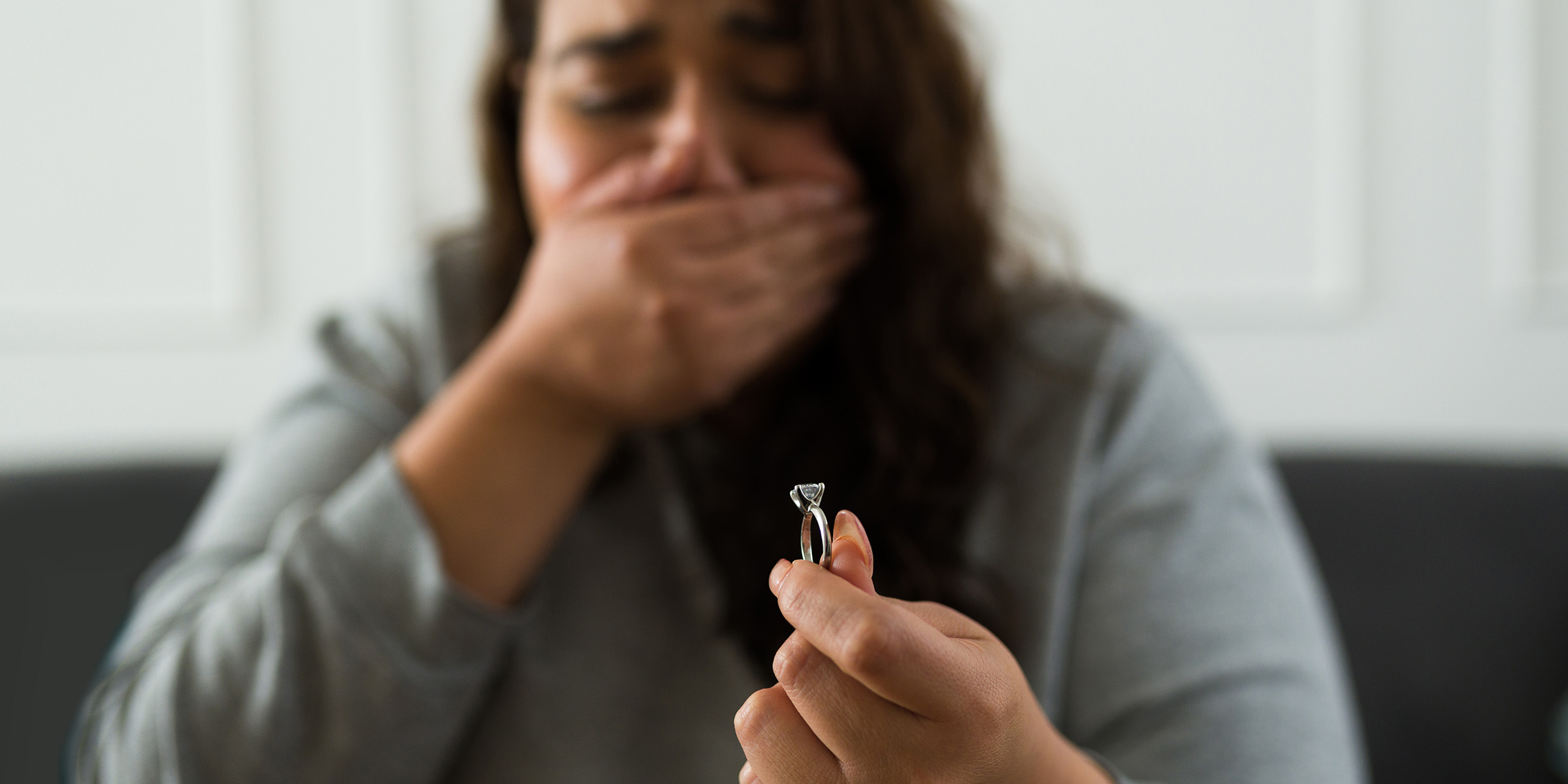 Une femme qui se couvre la bouche et tient une bague | Source : Getty Images