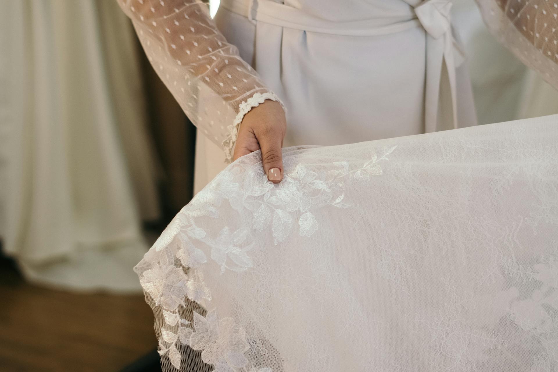 Une femme tenant une robe de mariée en dentelle | Source : Pexels