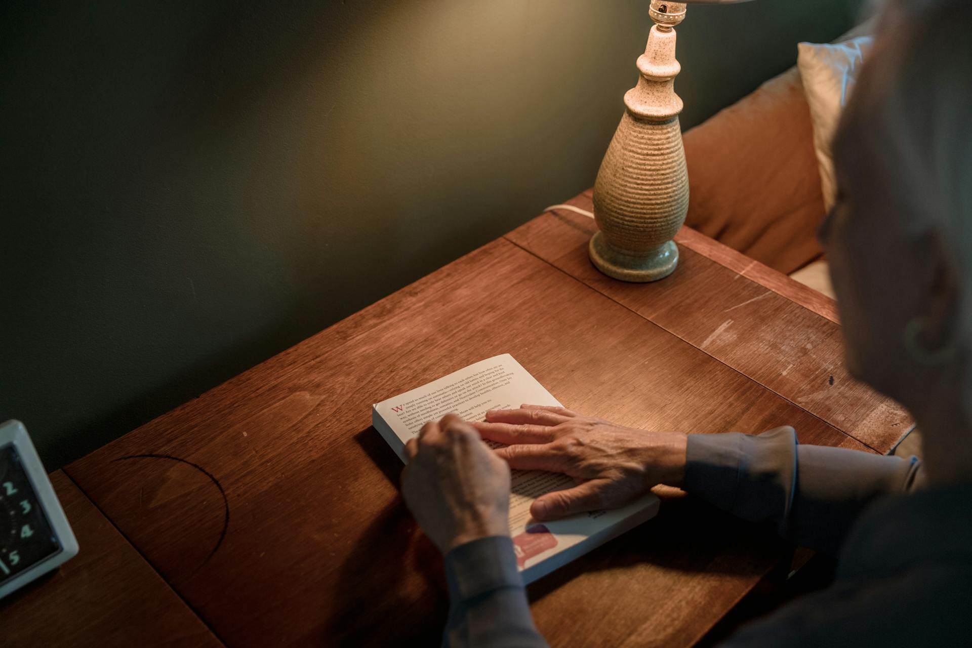 Une femme âgée tenant un livre au-dessus d'un bureau | Source : Pexels