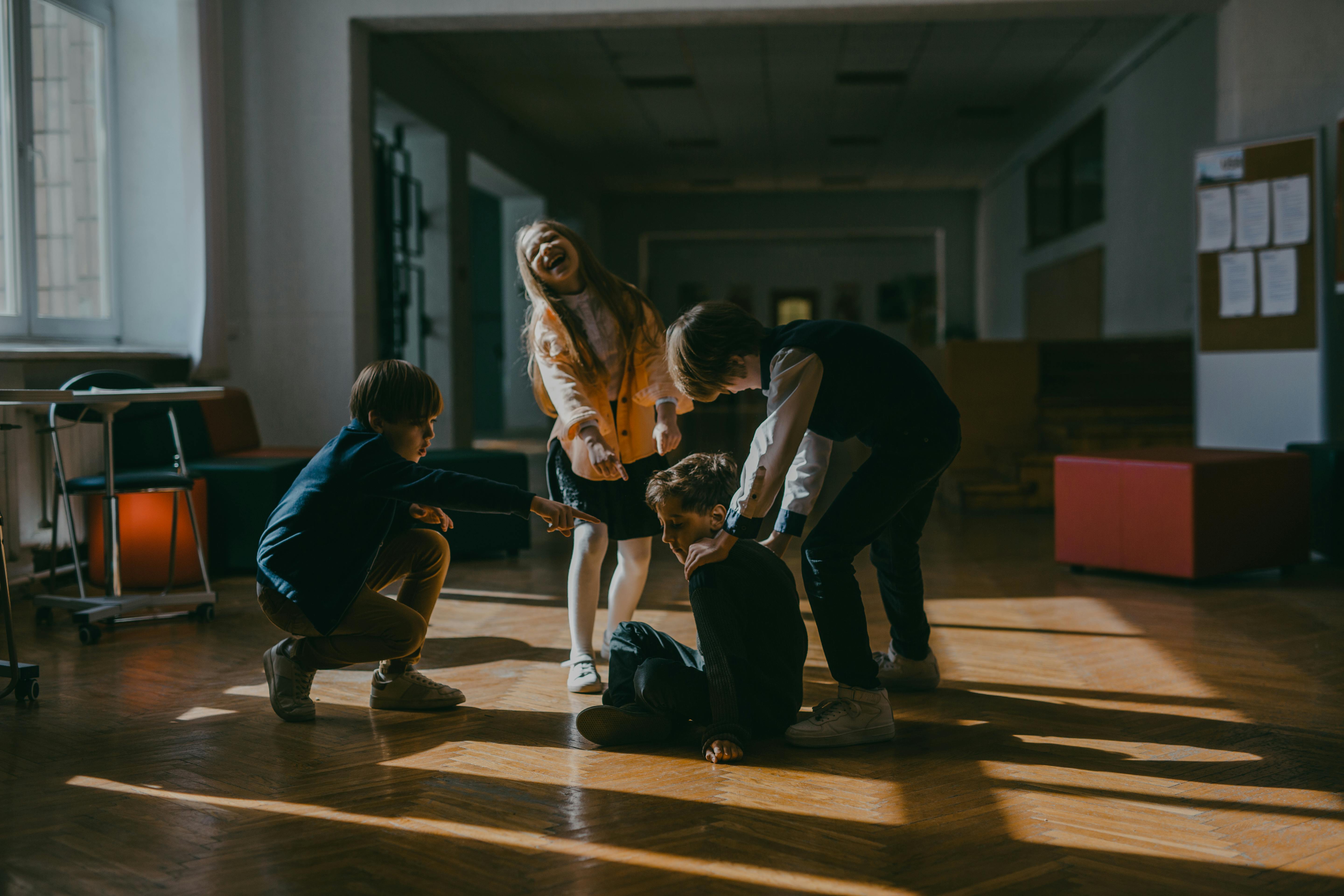 Un groupe d'enfants montre du doigt un camarade de classe assis et se moque de lui, capturant ainsi un moment d'intimidation dans un cadre scolaire. | Source : Pexels