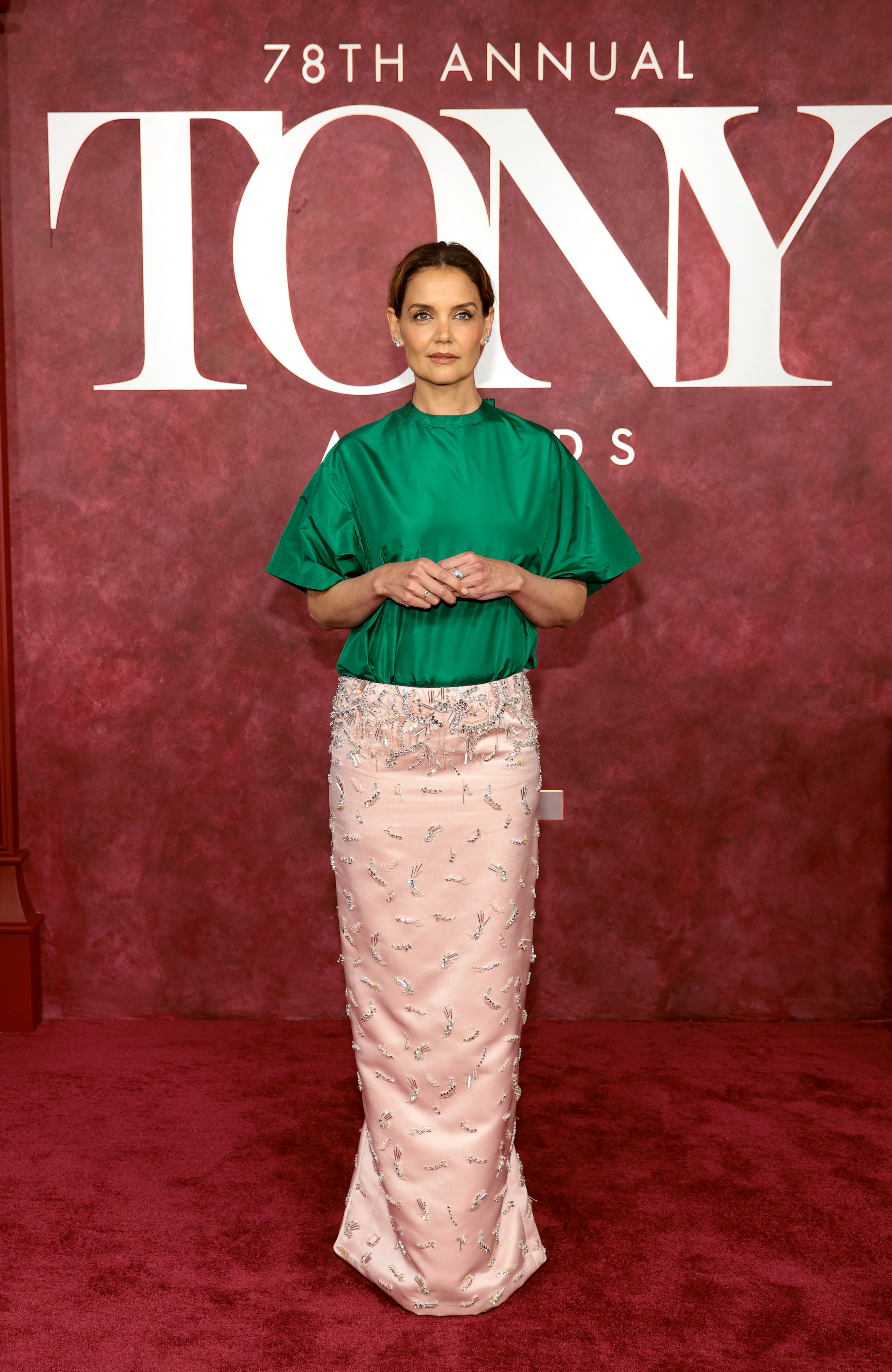 Encadrée par le lettrage officiel des Tony Awards, Katie Holmes adopte une position large, les mains délicatement jointes. La composition de la tête aux pieds met en valeur l'équilibre non conventionnel du vêtement entre le volume, la brillance et les détails ornés.