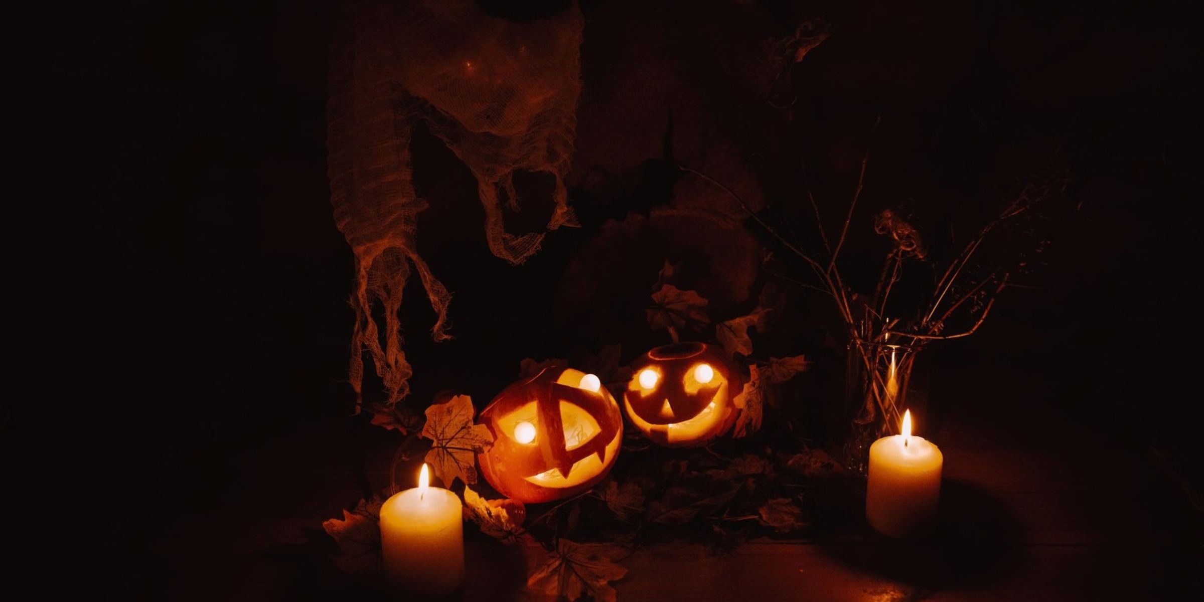 Une décoration d'Halloween sombre avec des citrouilles lumineuses et des bougies qui projettent des ombres inquiétantes | Source : Pexels