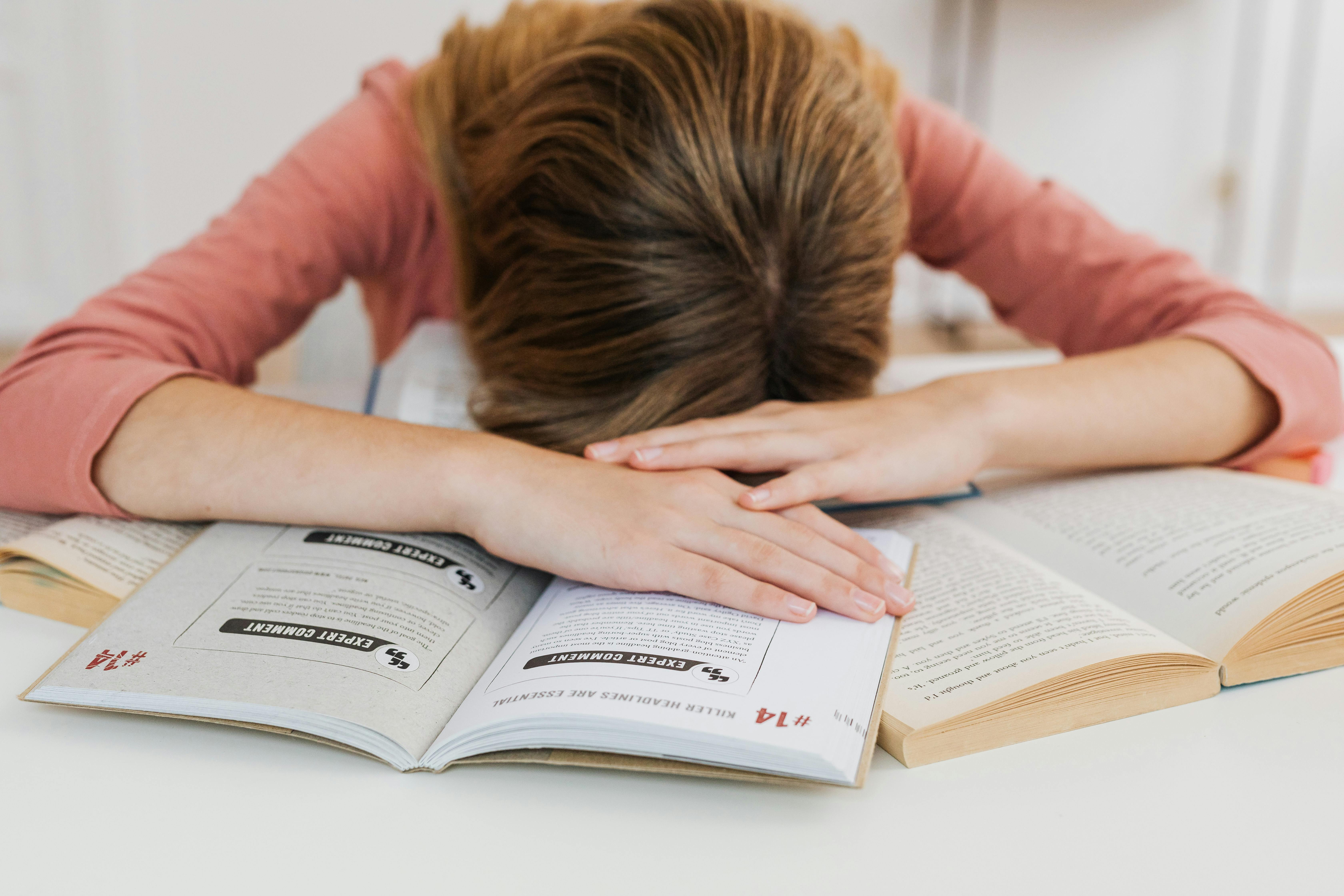 Une fille stressée allongée sur ses livres | Source : Pexels