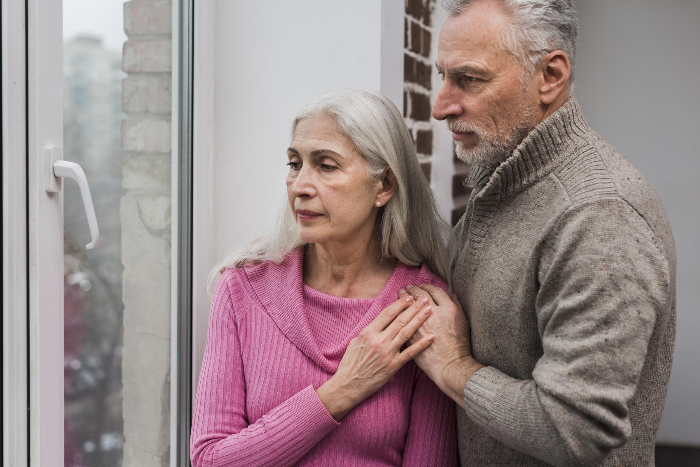 Un couple âgé regardant par la fenêtre | Source : Freepik