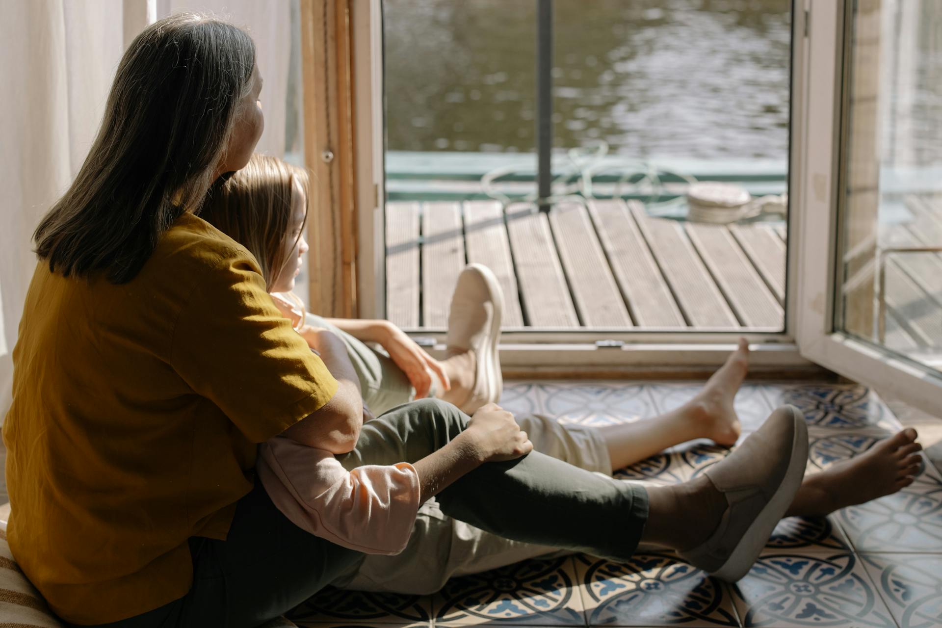 Une grand-mère assise avec sa petite-fille sur le sol et regardant à l'extérieur | Source : Pexels