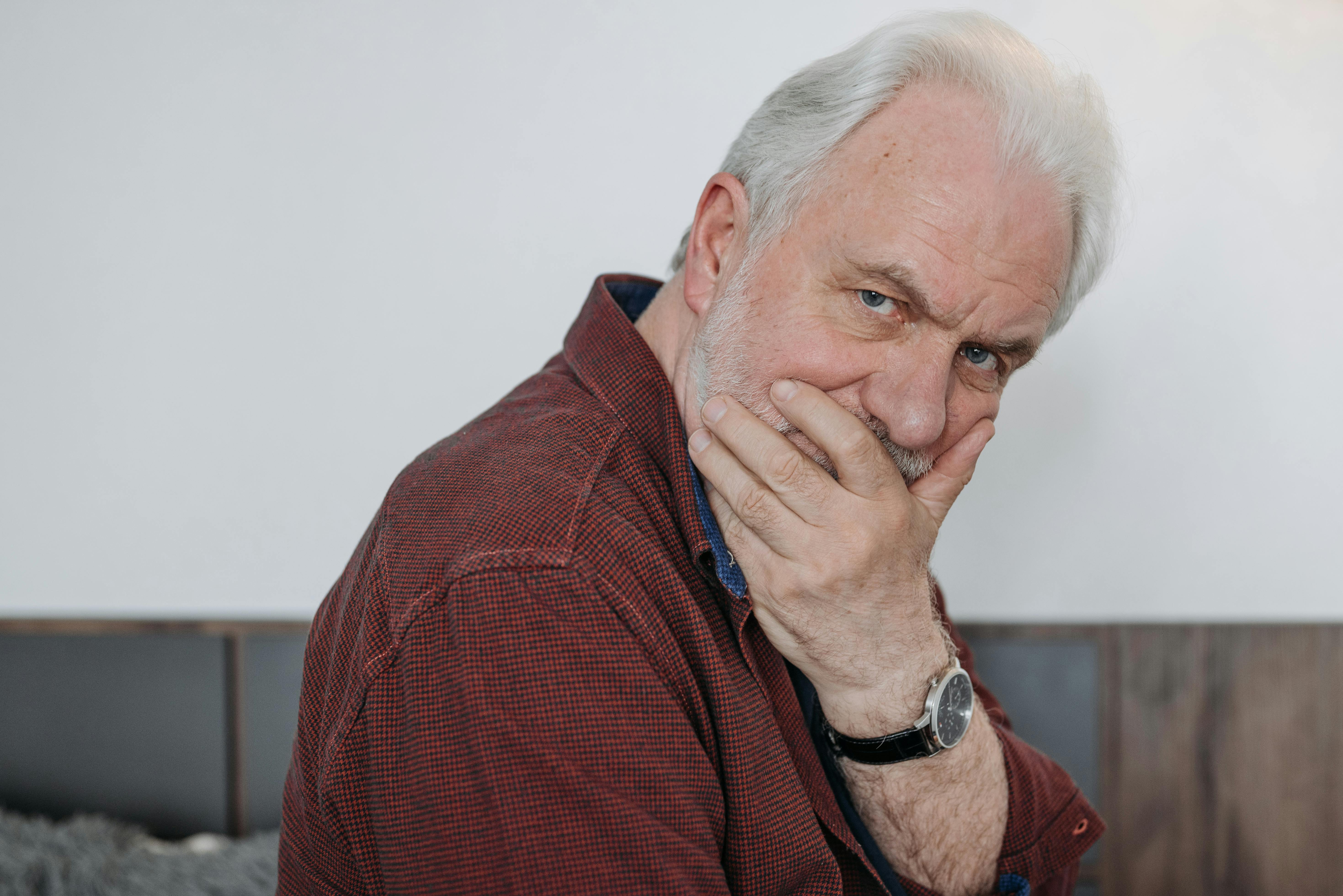 Un homme plus âgé se couvrant la bouche | Source : Pexels