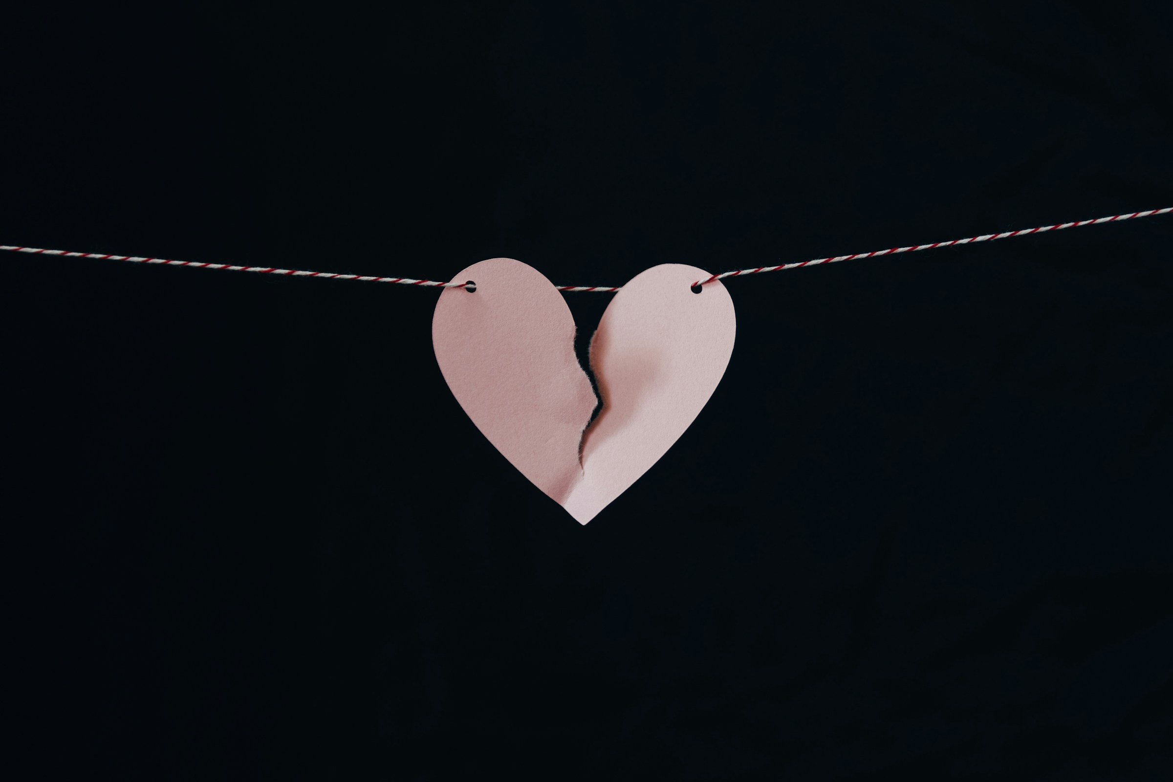 Un cœur en papier rose brisé accroché à un fil de fer | Source : Unsplash