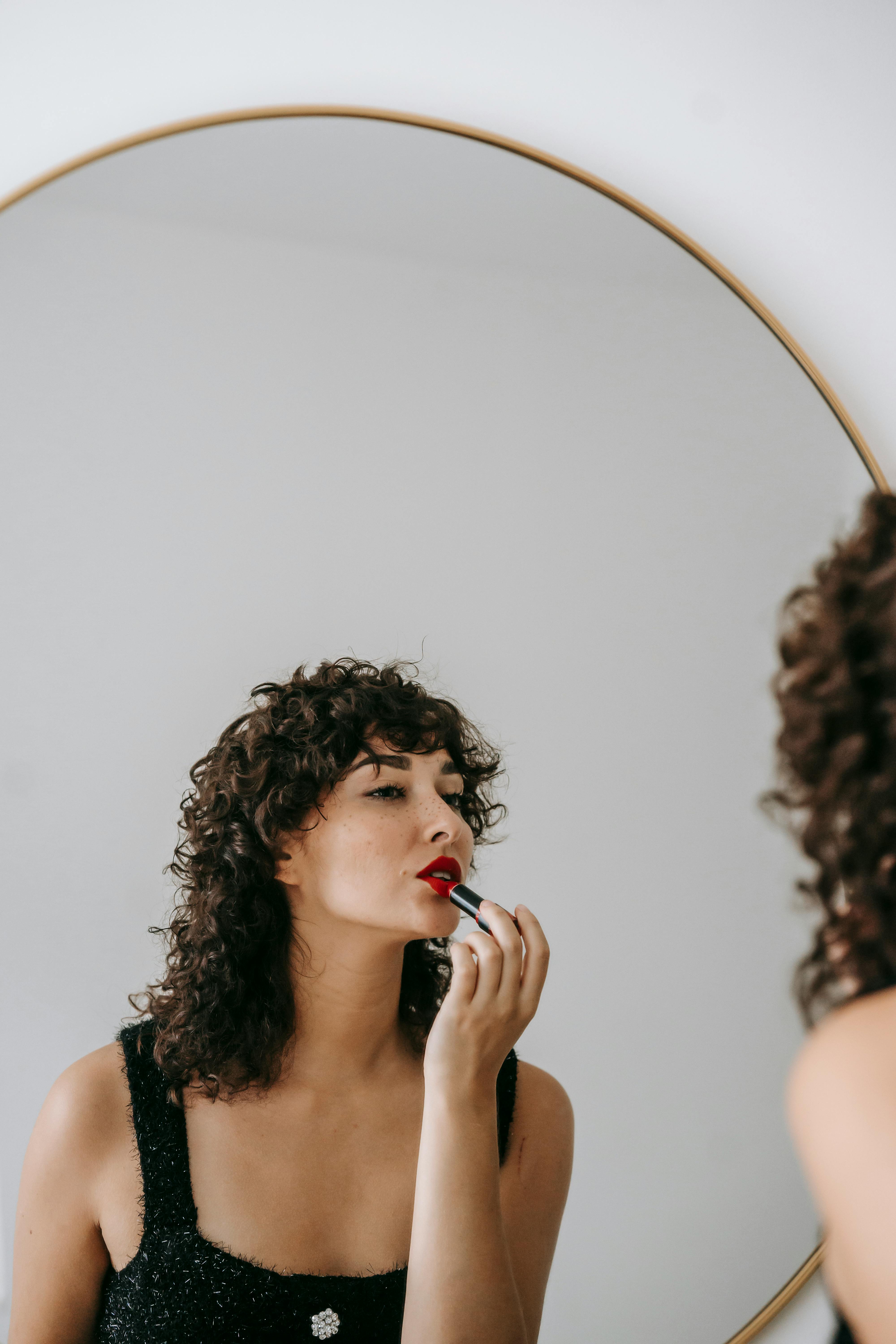 Une femme appliquant du rouge à lèvres rouge | Source : Pexels