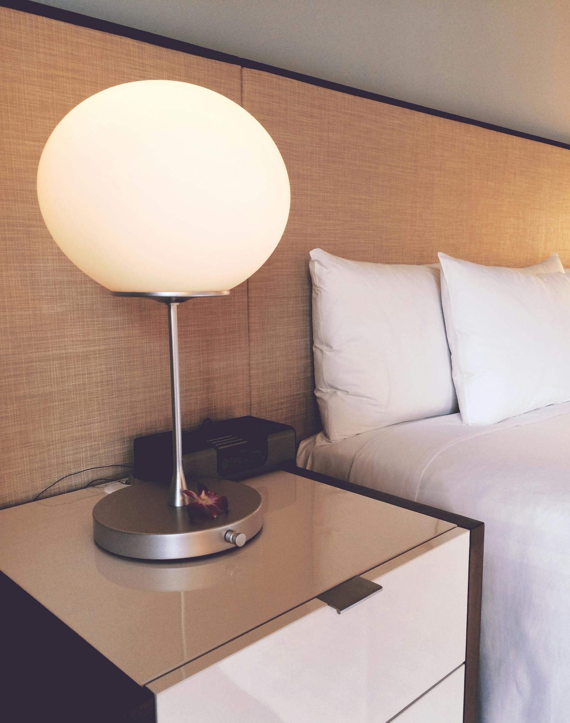 Une lampe de bureau blanche et argentée à côté d'un lit | Source : Pexels