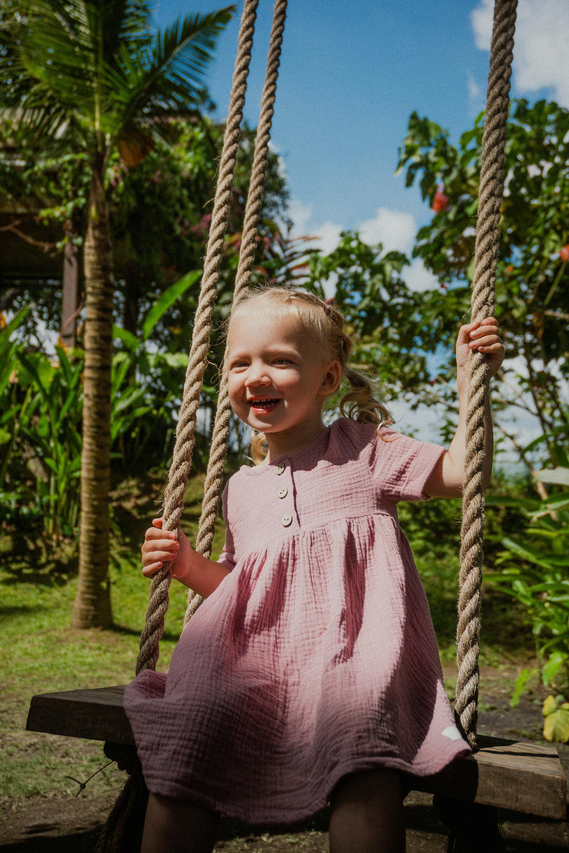 Une petite fille souriante sur une balançoire | Source : Pexels
