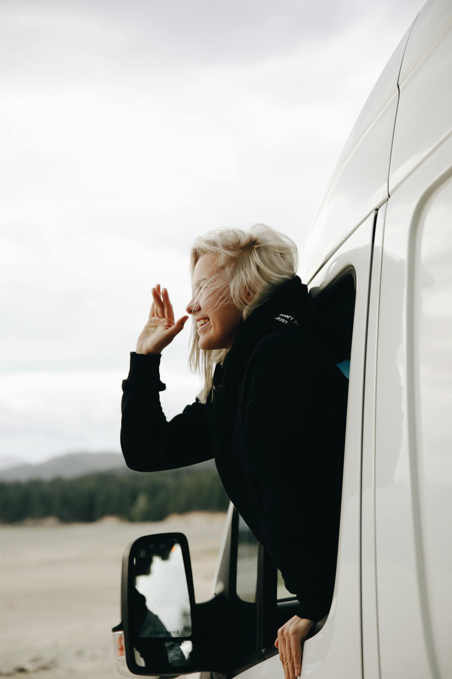 Une femme fait un signe de la main depuis un véhicule | Source : Pexels