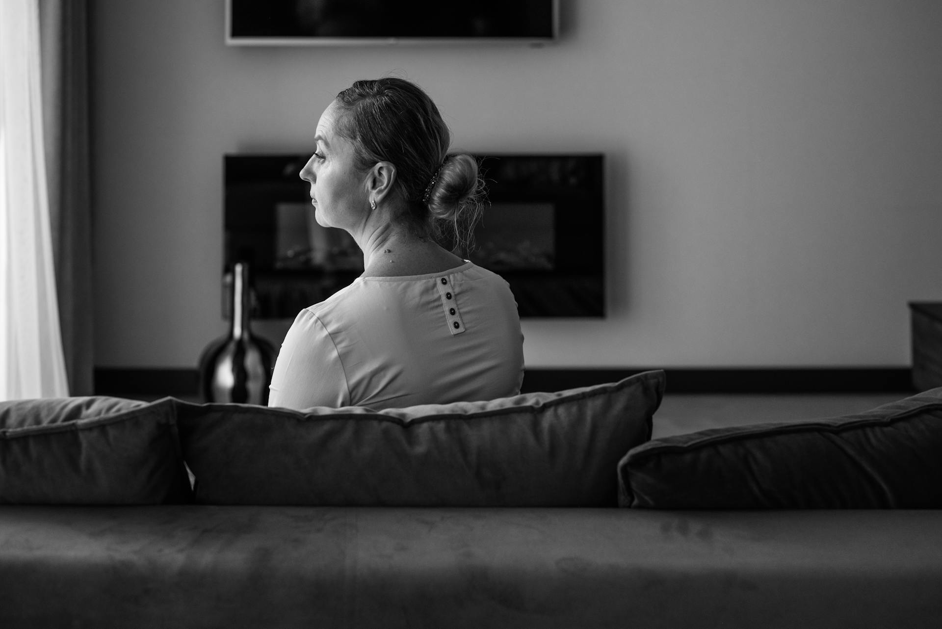 Photo en niveaux de gris d'une femme triste assise dans une pièce | Source : Pexels