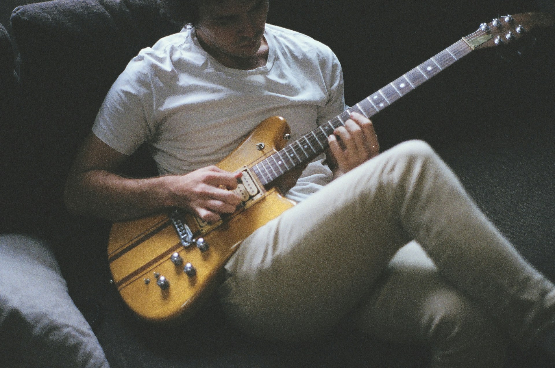 Un homme jouant de la guitare électrique sur un canapé | Source : Unsplash