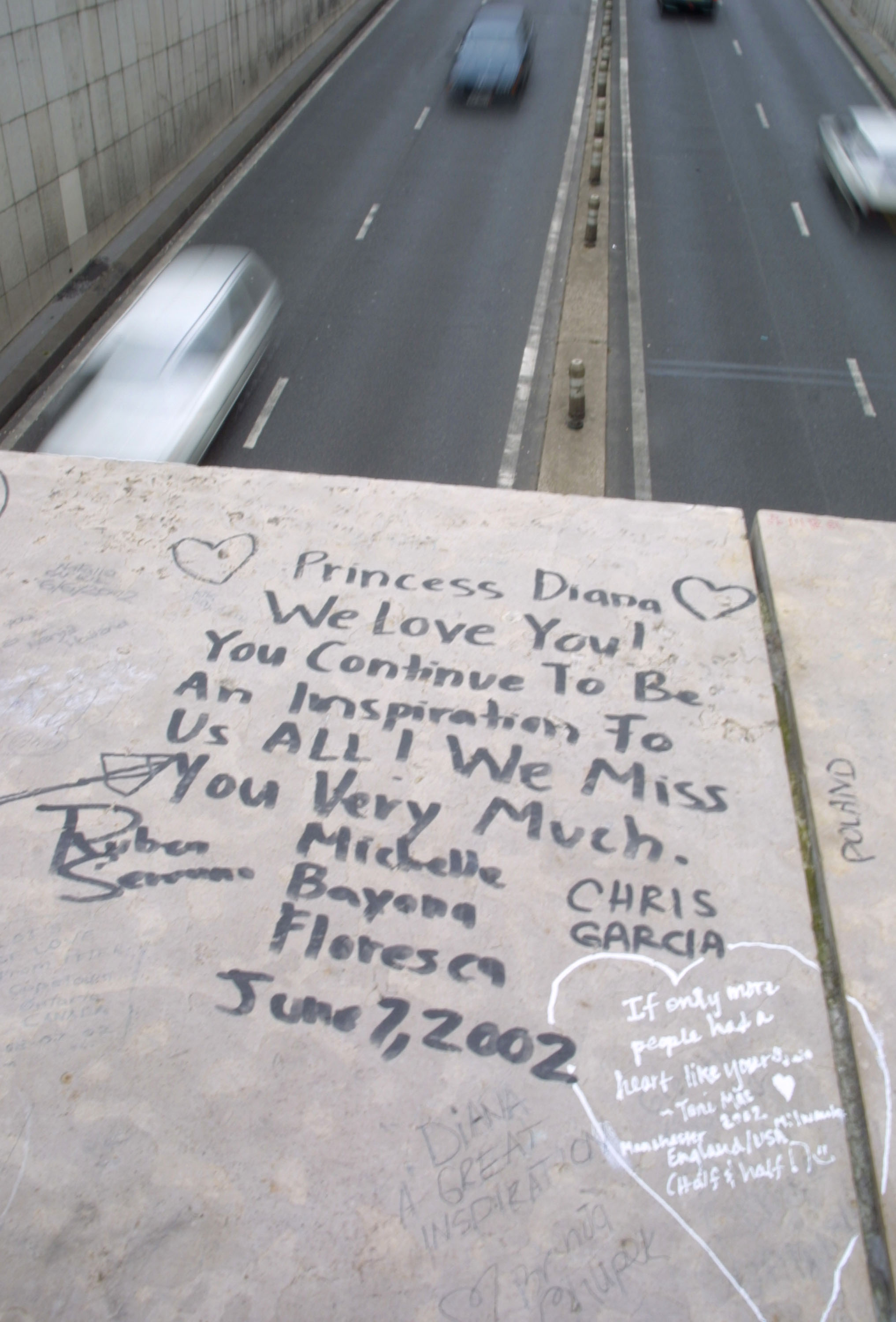 Un fan rend hommage à la princesse de Galles Diana avec une note laissée près du site de l'accident lors du cinquième anniversaire de sa mort, le 30 août 2002 à Paris, France | Source : Getty Images