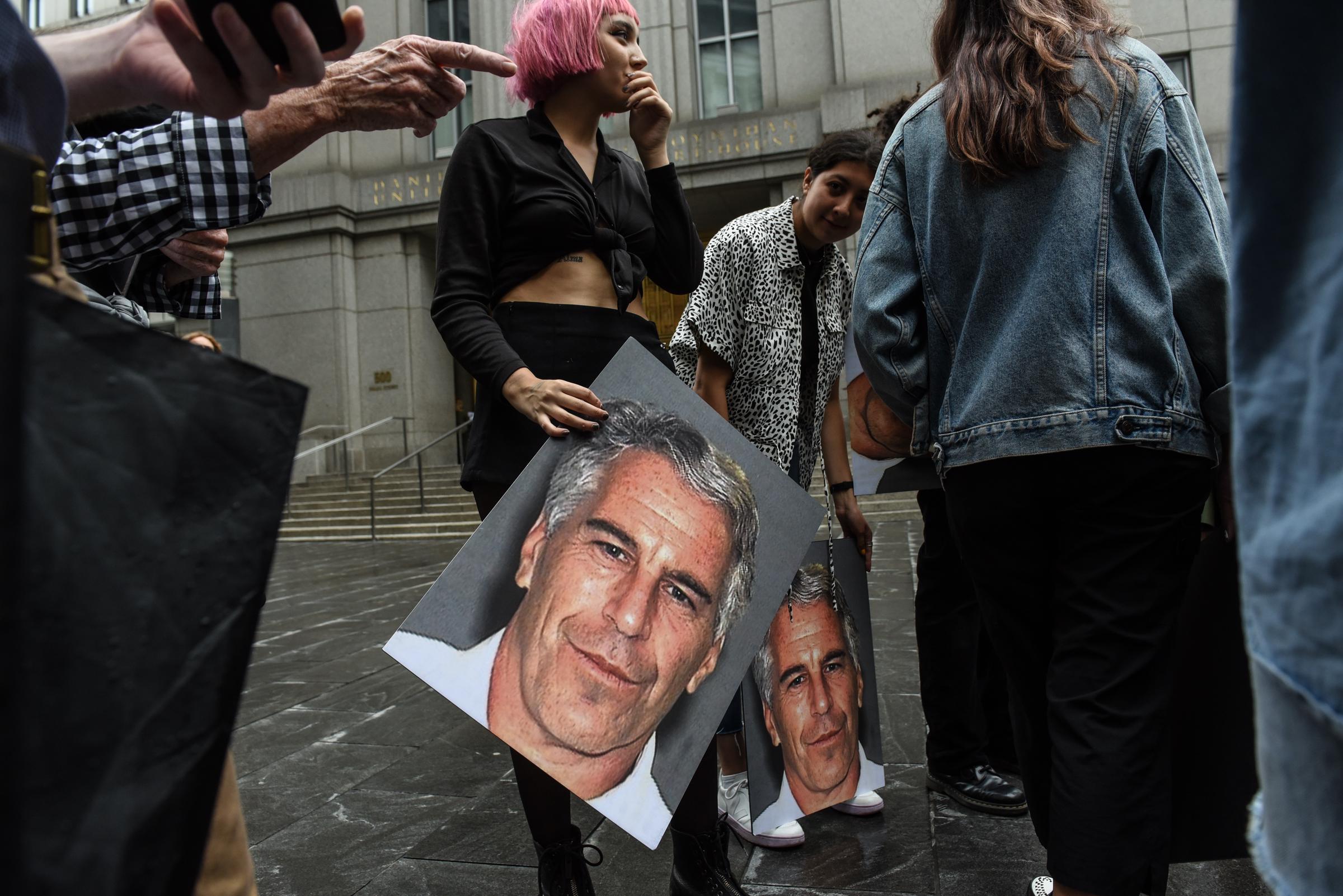 Un groupe de protestataires appelé « Hot Mess » brandit des pancartes à l'effigie de Jeffrey Epstein devant le tribunal fédéral, le 8 juillet 2019, à New York. | Source : Getty Images
