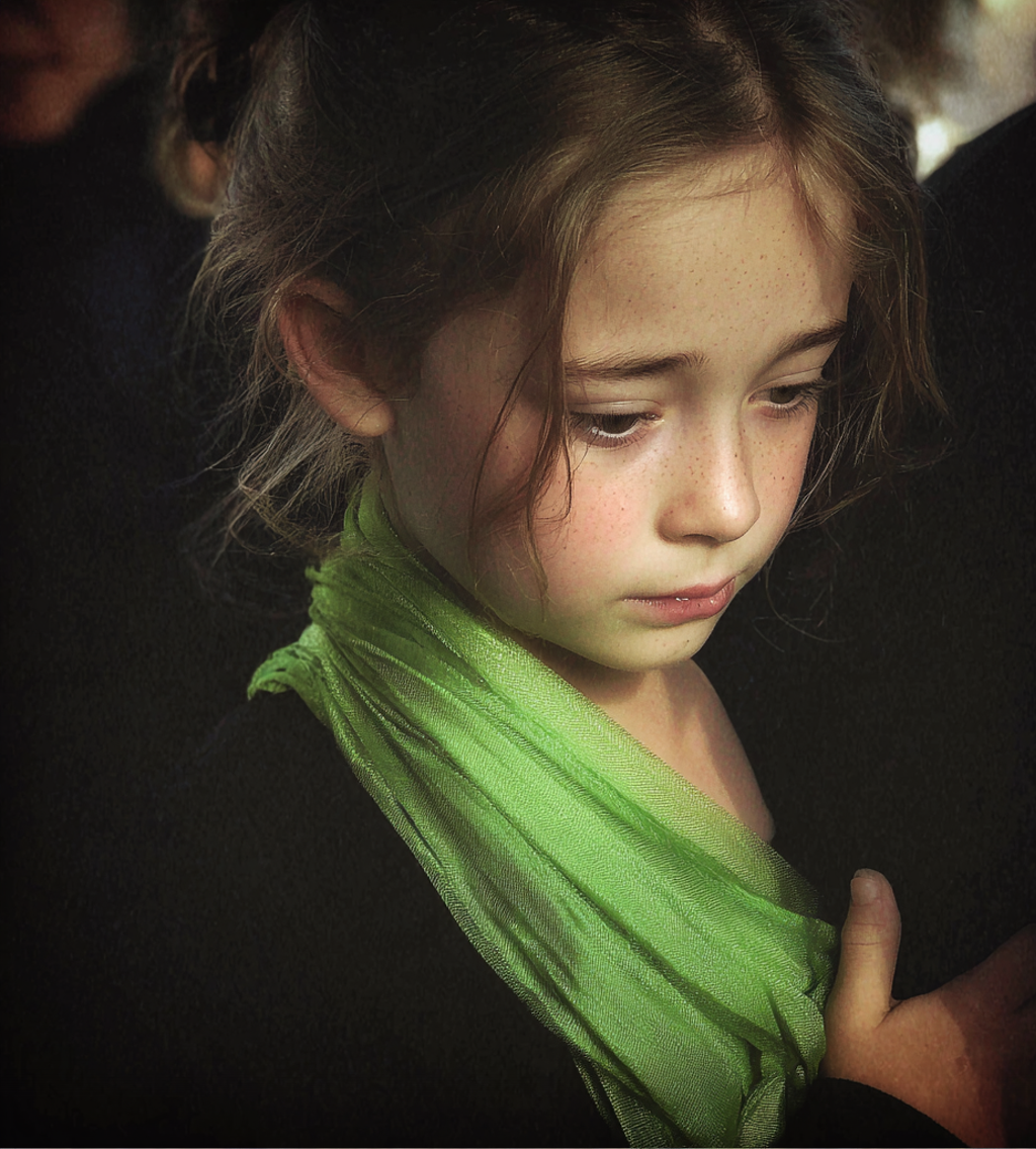 Une petite fille tenant une écharpe verte | Source : Midjourney