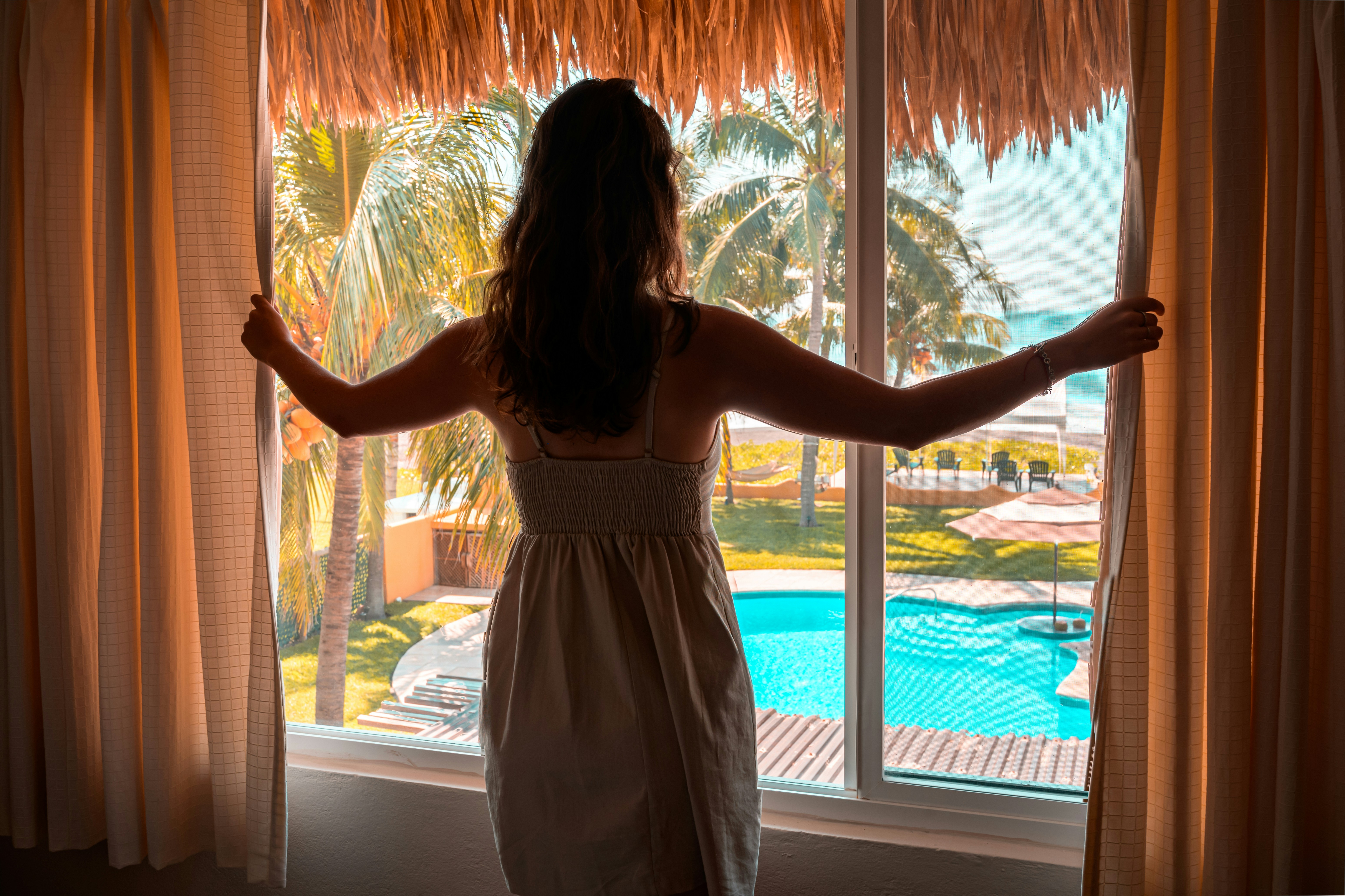 Une personne se tenant à la fenêtre d’une chambre d’hôtel | Source : Unsplash