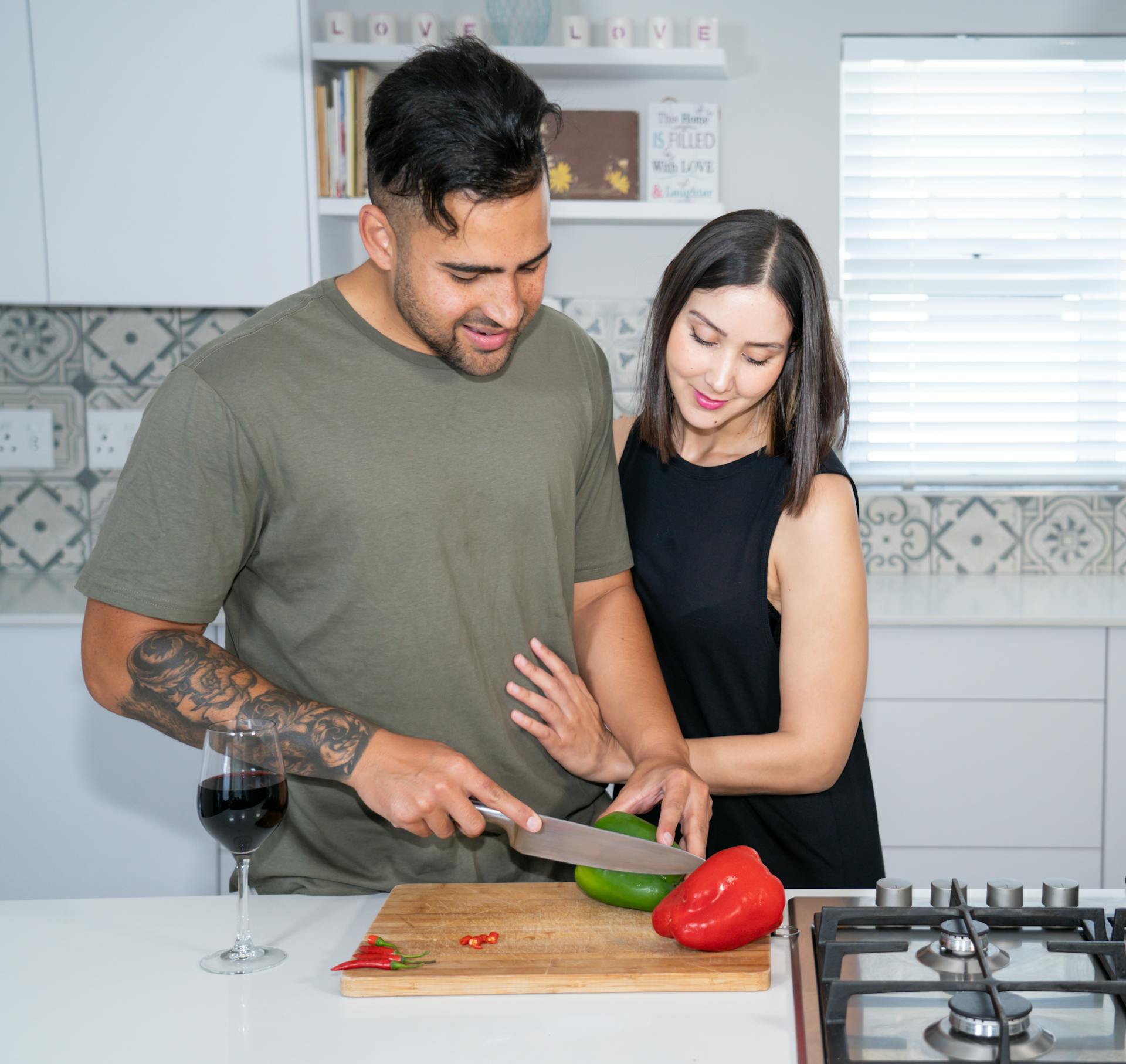 Une femme regarde son mari couper des légumes dans la cuisine | Source : Pexels