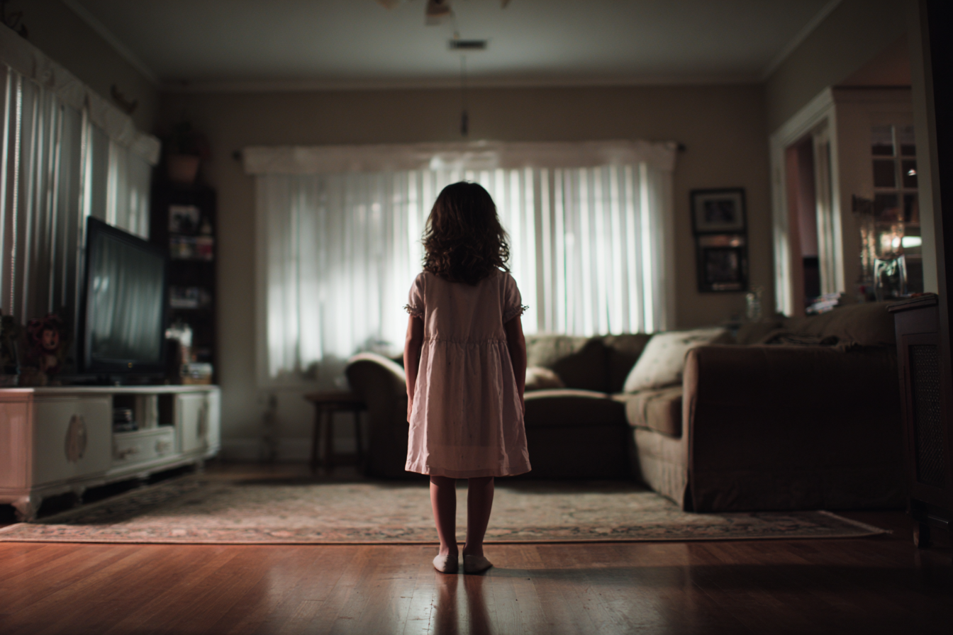 Une petite fille debout dans un salon | Source : Midjourney