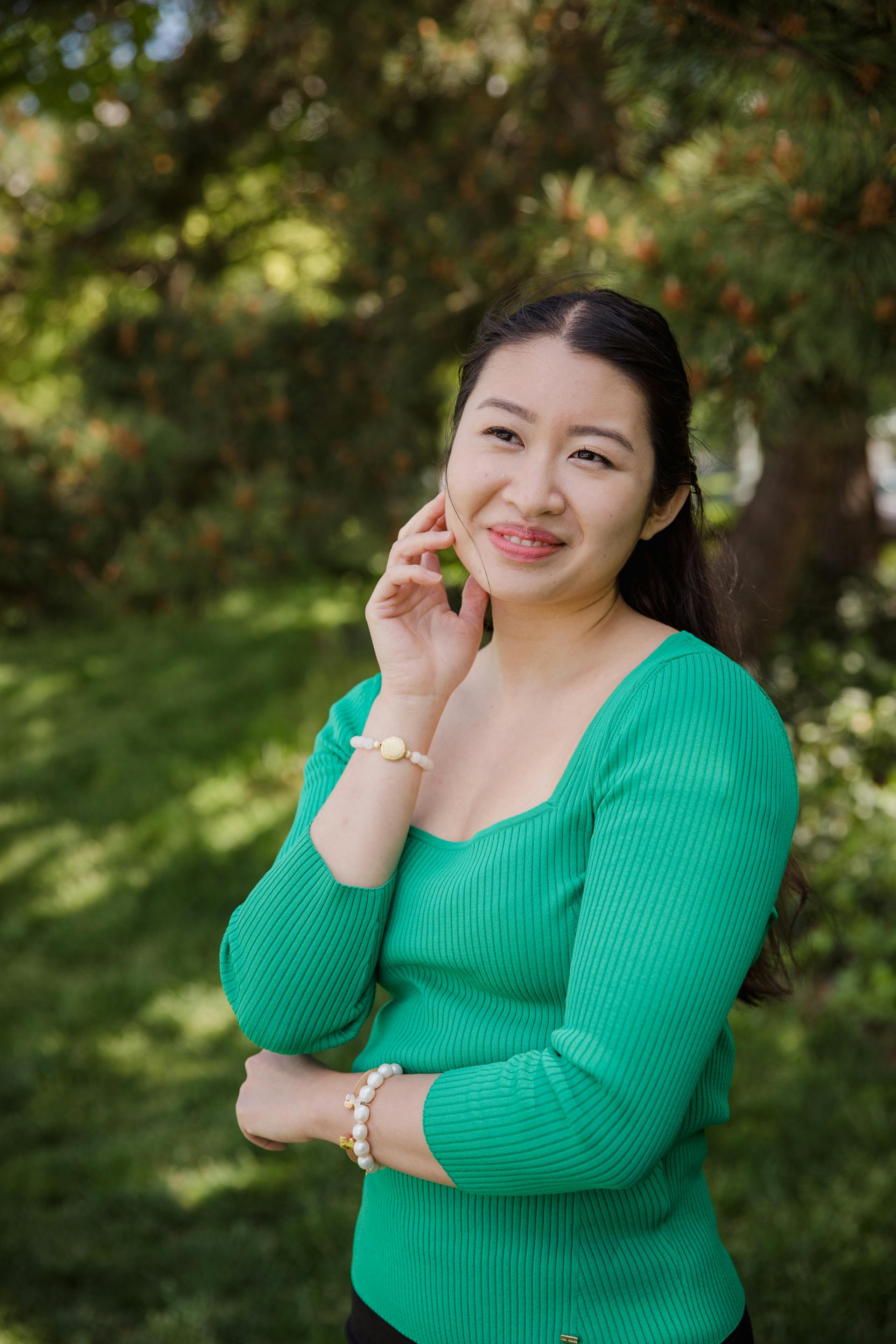 Une belle femme portant une chemise verte et souriant à l'extérieur | Source : Pexels