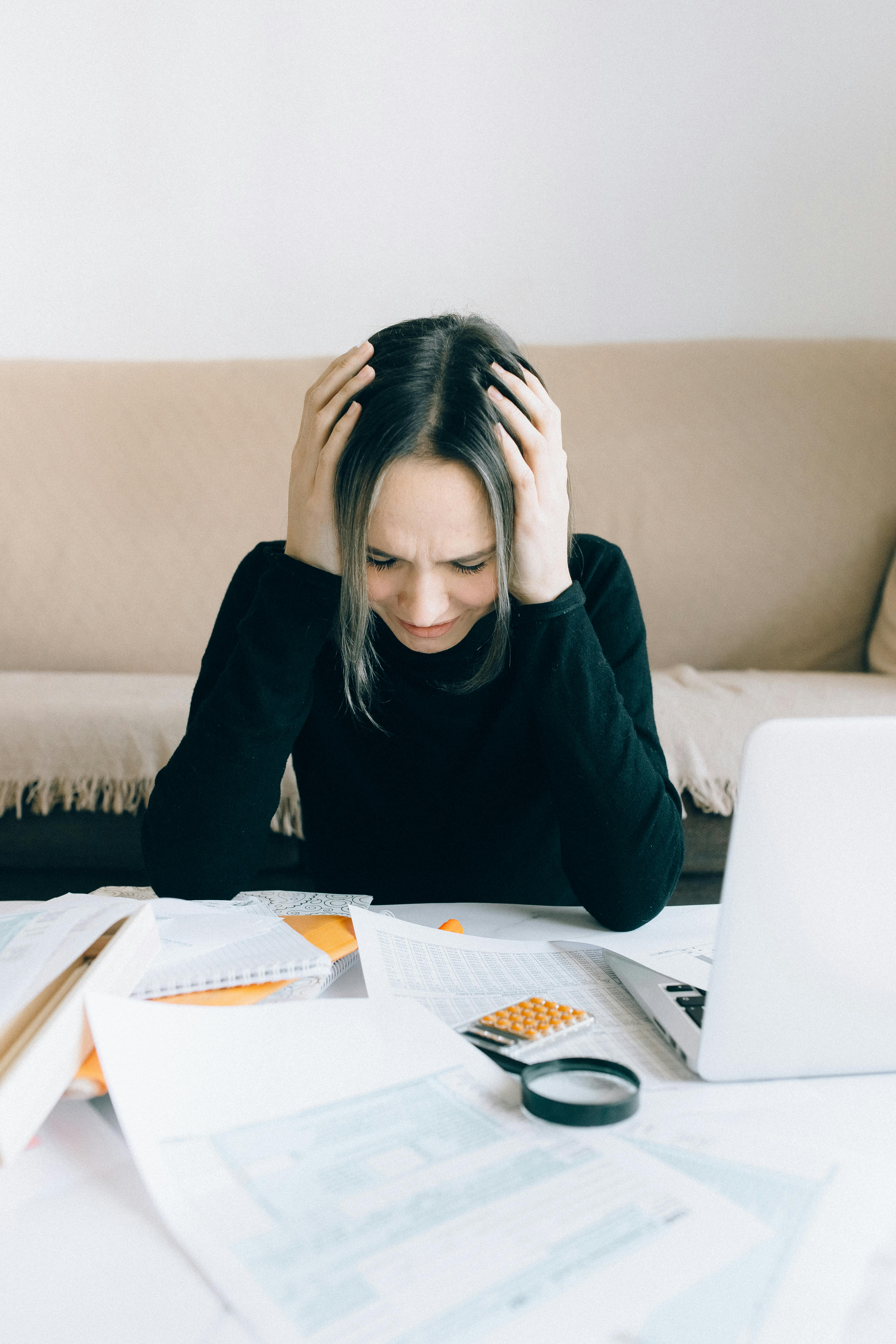 Une femme assise à une table et se tenant la tête | Source : Pexels