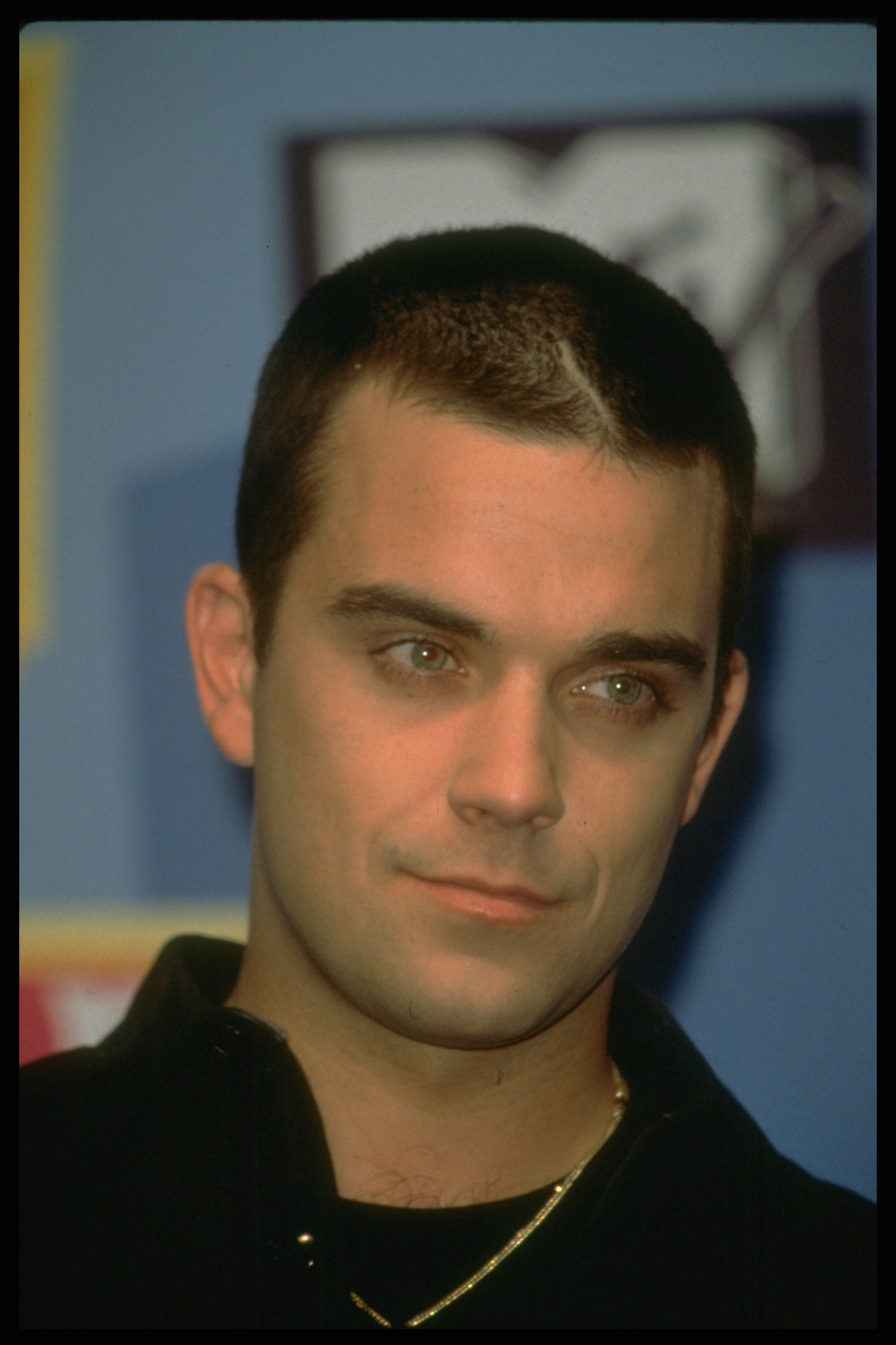 Robbie Williams assiste aux Europe Music Awards à Milan, en Italie, en 1998, arborant une coupe de cheveux très courte et un regard confiant. À cette époque, sa carrière solo bat son plein, et son nouveau look avant-gardiste reflète une star qui s'impose fermement sous les feux de la rampe.