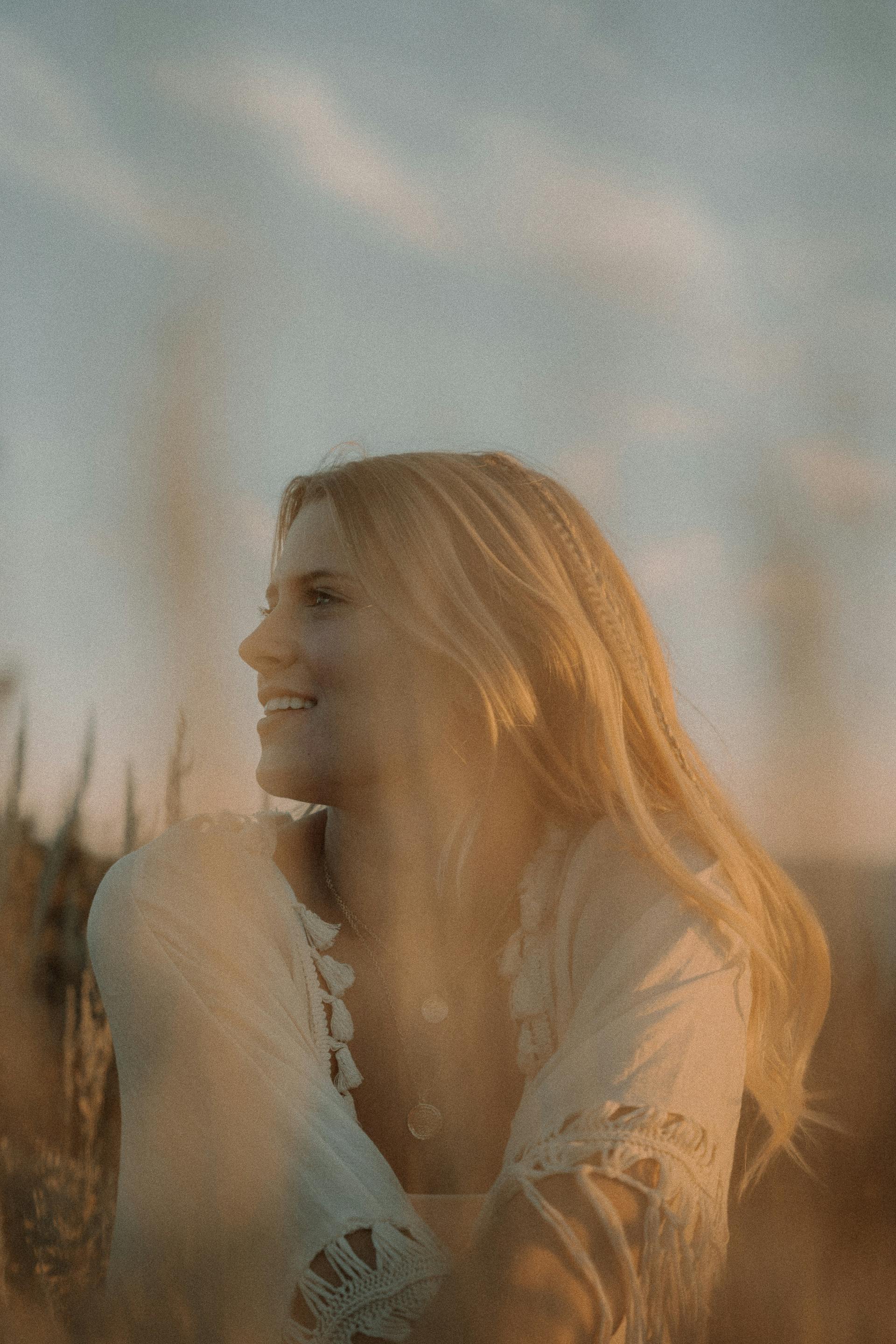 Une femme heureuse assise à l'extérieur | Source : Pexels