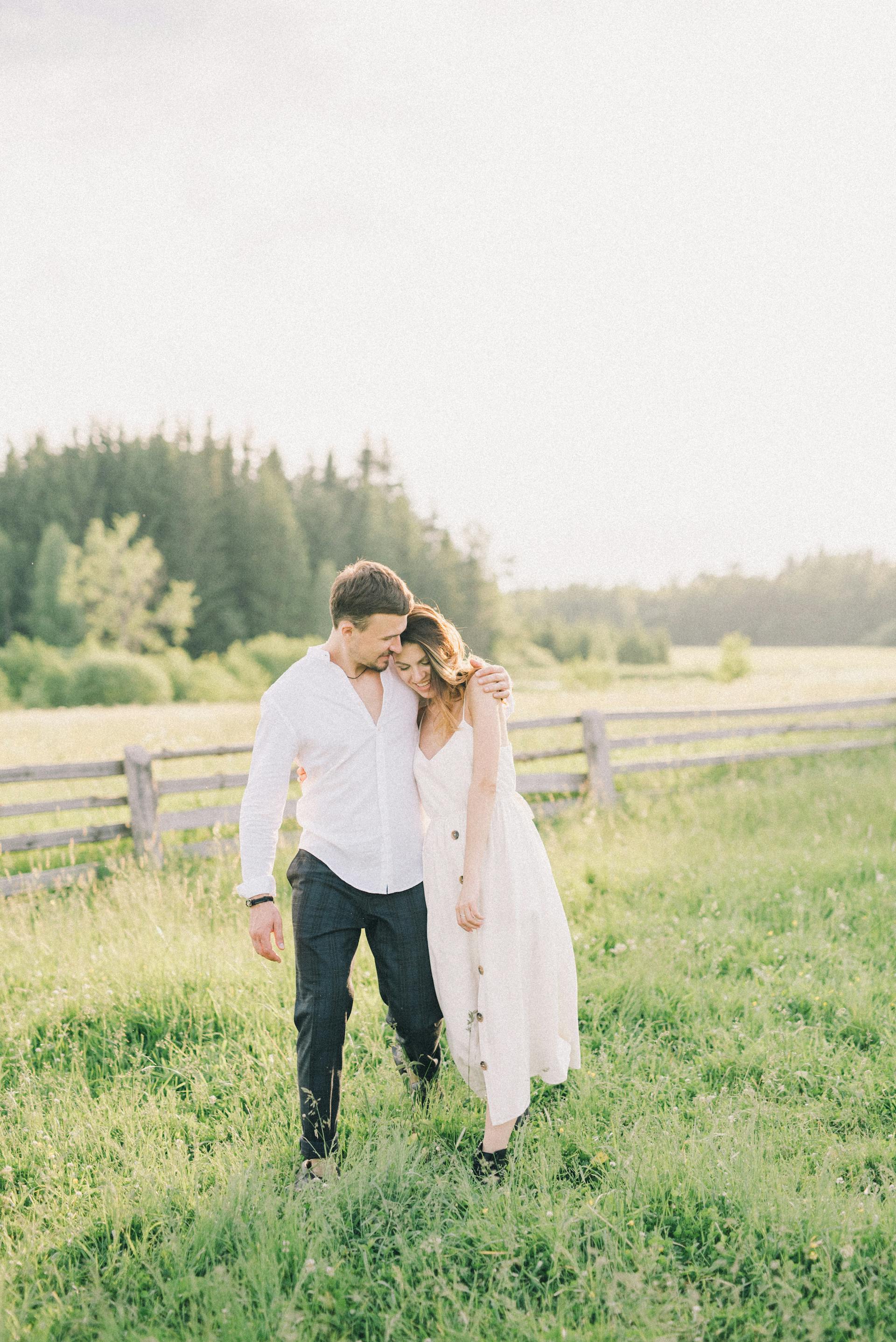 Un couple heureux se promenant dans un champ | Source : Pexels