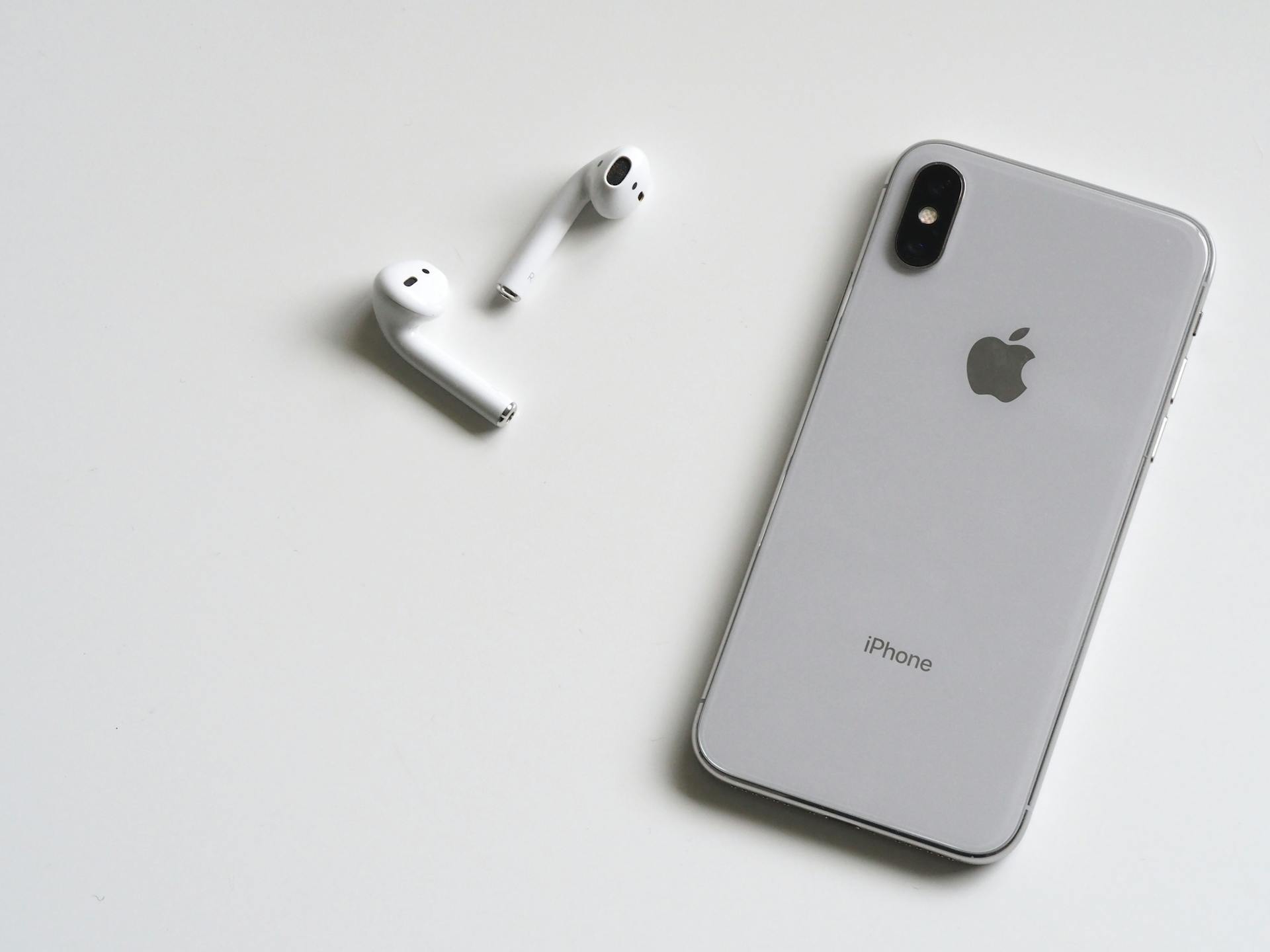 Un iPhone X argenté avec des Airpods | Source : Pexels