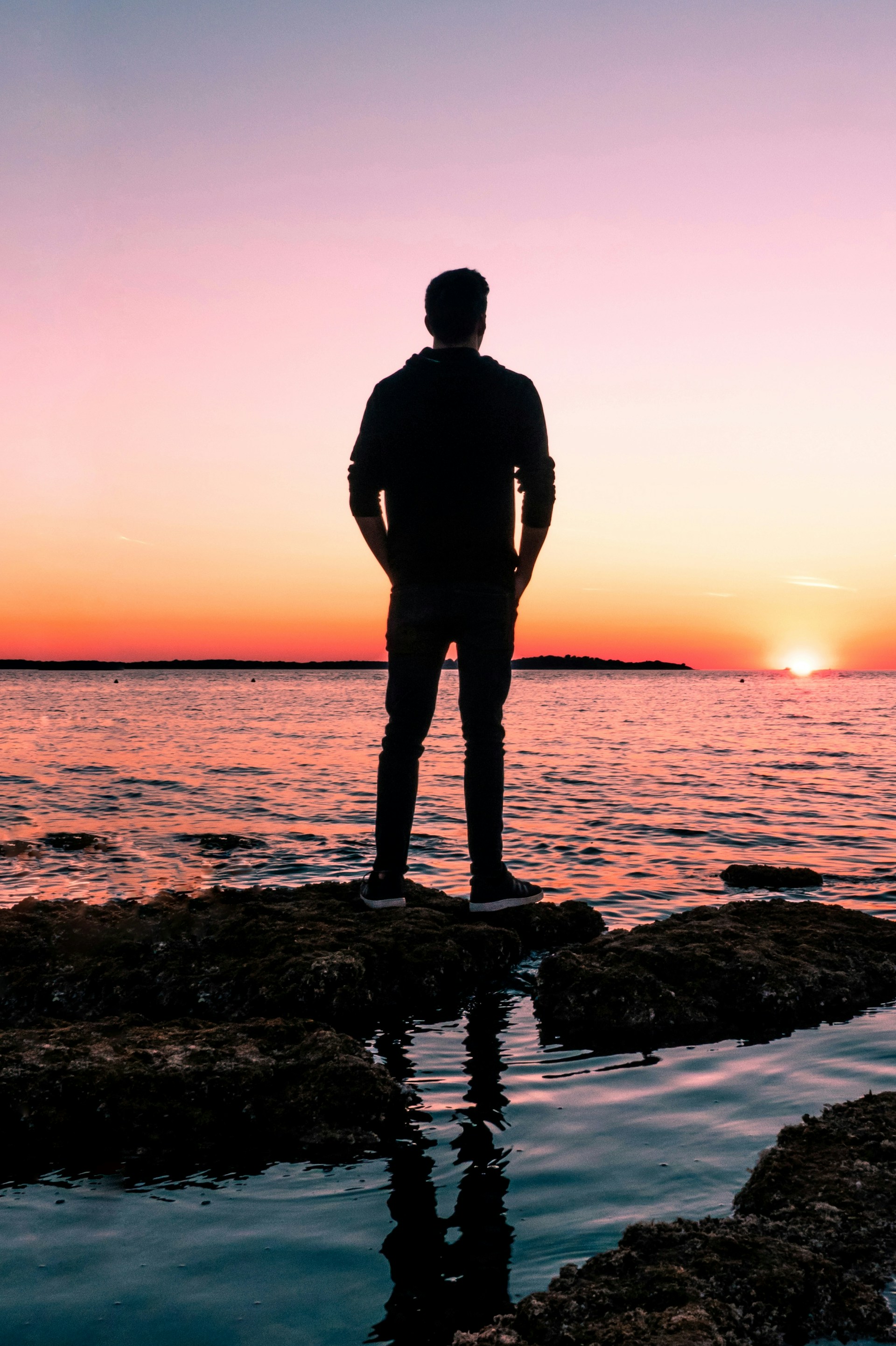 Un homme observant la lumière dorée du soleil depuis le rivage lors d'une soirée pittoresque | Source : Unsplash