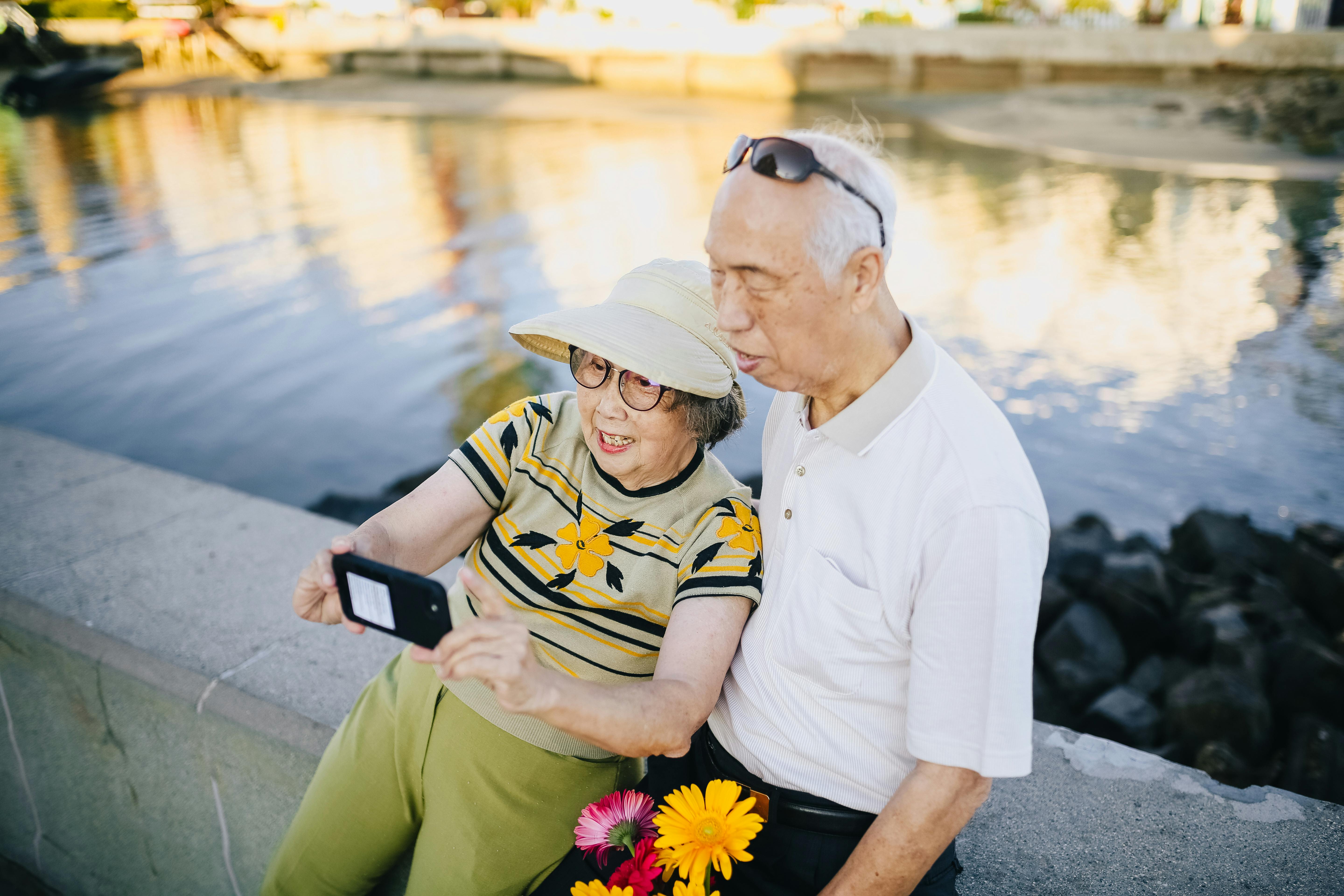 Couple âgé sur un banc en béton prenant un selfie | Source : Pexels