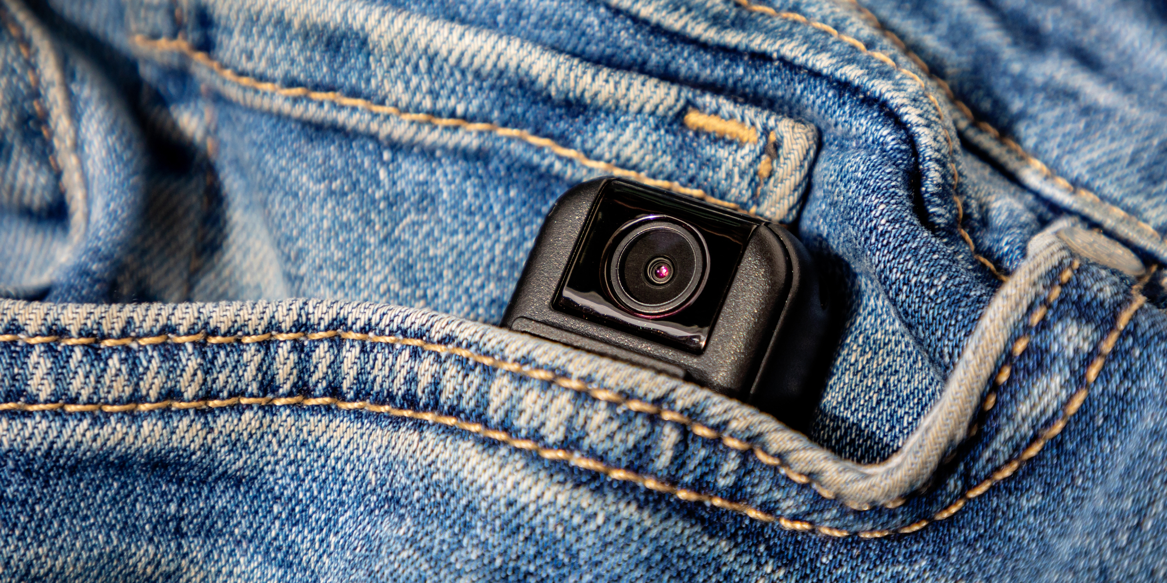 Une petite caméra cachée qui sort de la poche avant d'une paire de blue jeans | Source : Shutterstock