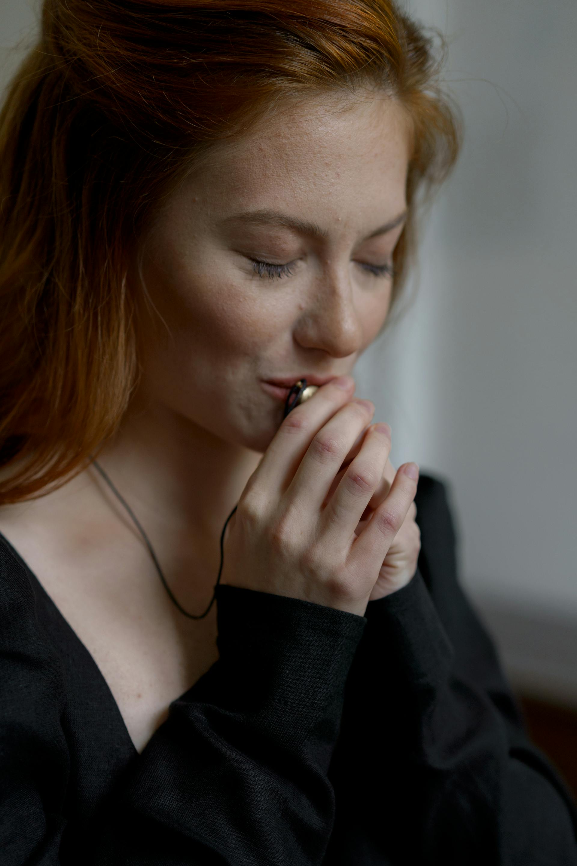 Une femme en robe noire embrassant son collier | Source : Pexels