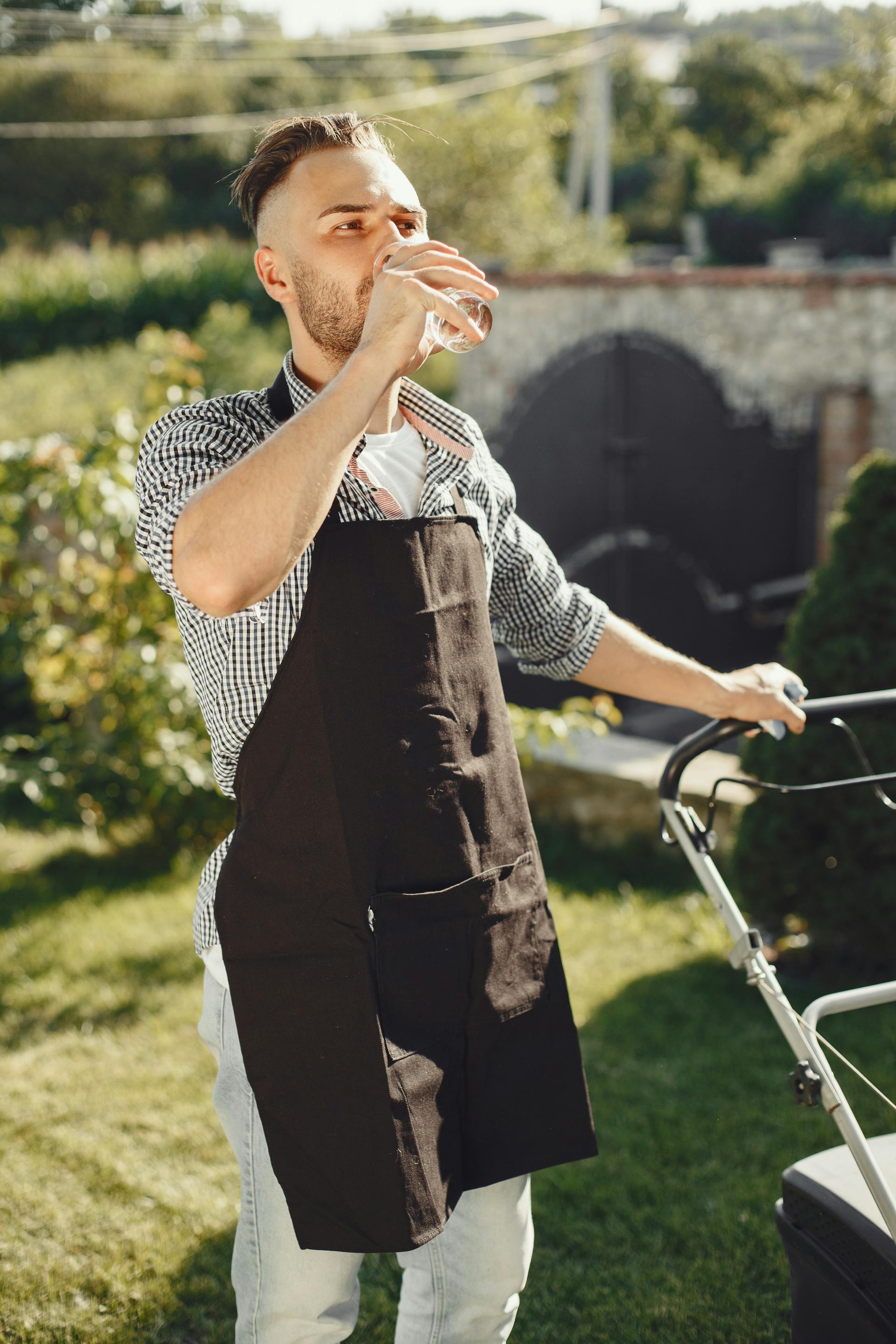 Un homme buvant de l'eau dans son jardin | Source : Pexels