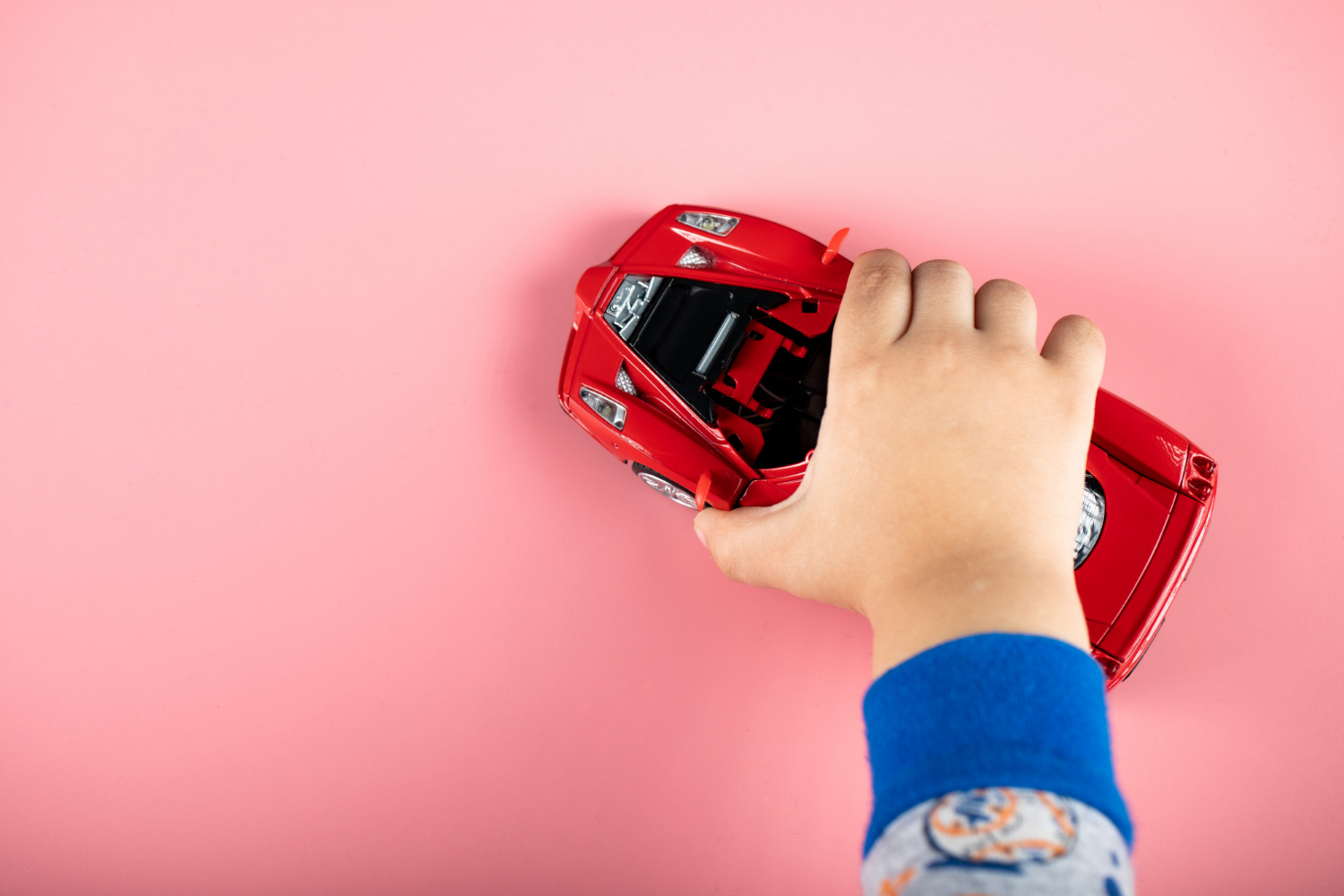 Un enfant qui joue avec une voiture rouge | Source : Freepik