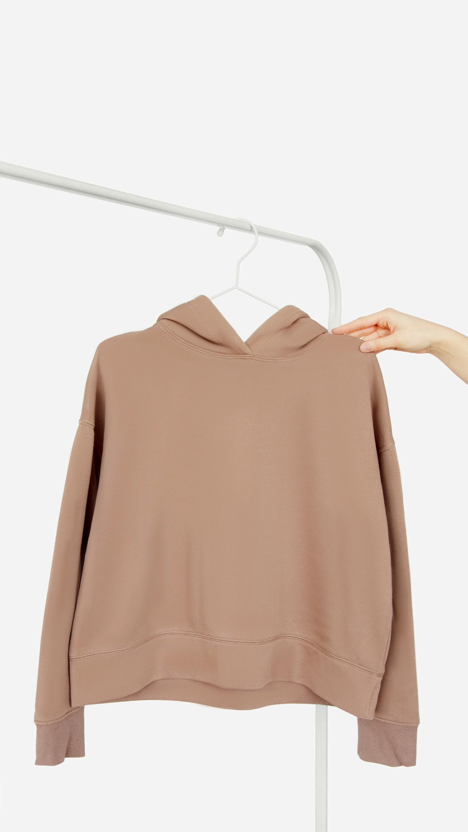 Une personne tenant un sweat à capuche rose poussiéreux | Source : Pexels
