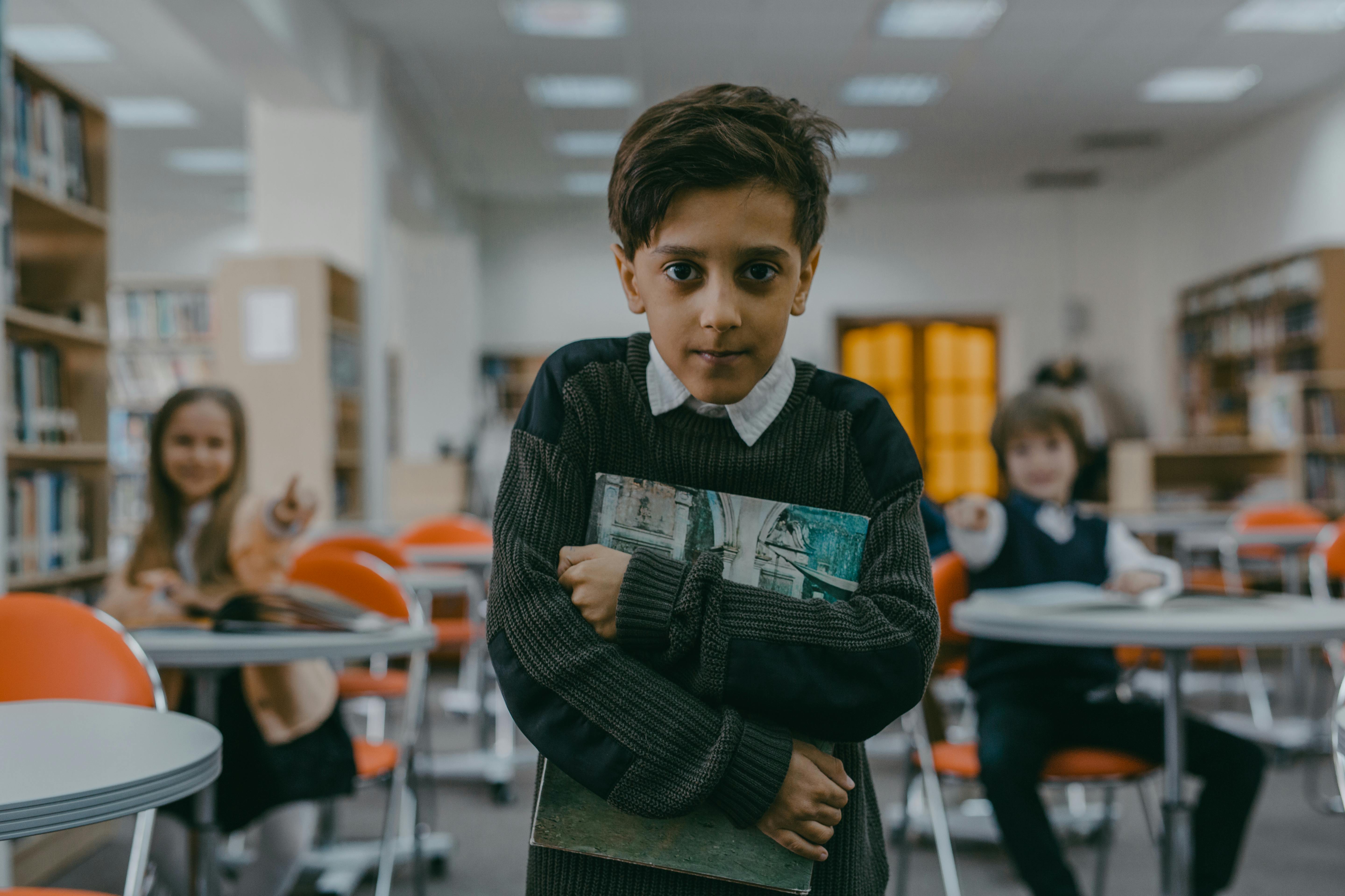 Un enfant serrant un livre dans ses bras avec un petit sourire | Source : Pexels