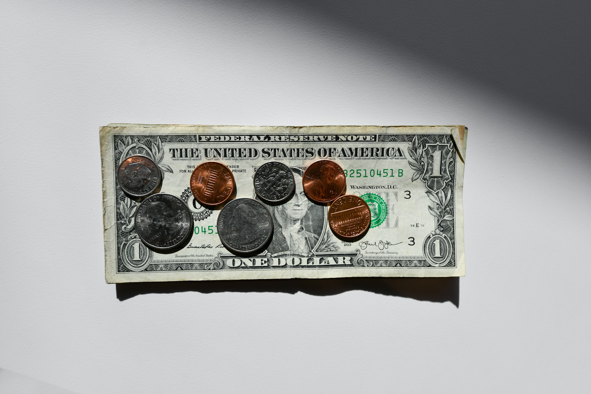 Pièces de monnaie sur une fine pile de billets d'un dollar | Source : Unsplash