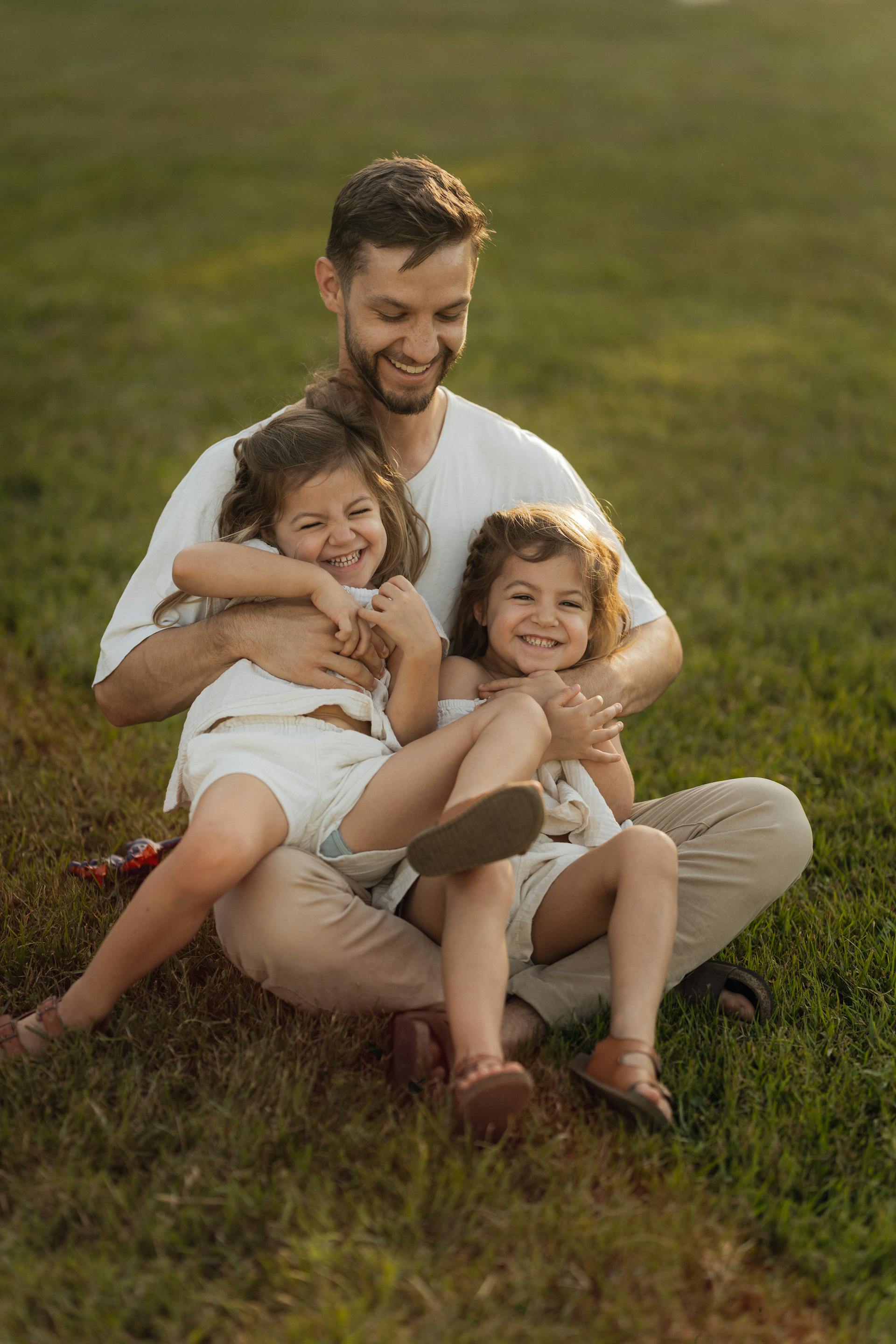 Un père jouant avec ses filles sur la pelouse | Source : Pexels