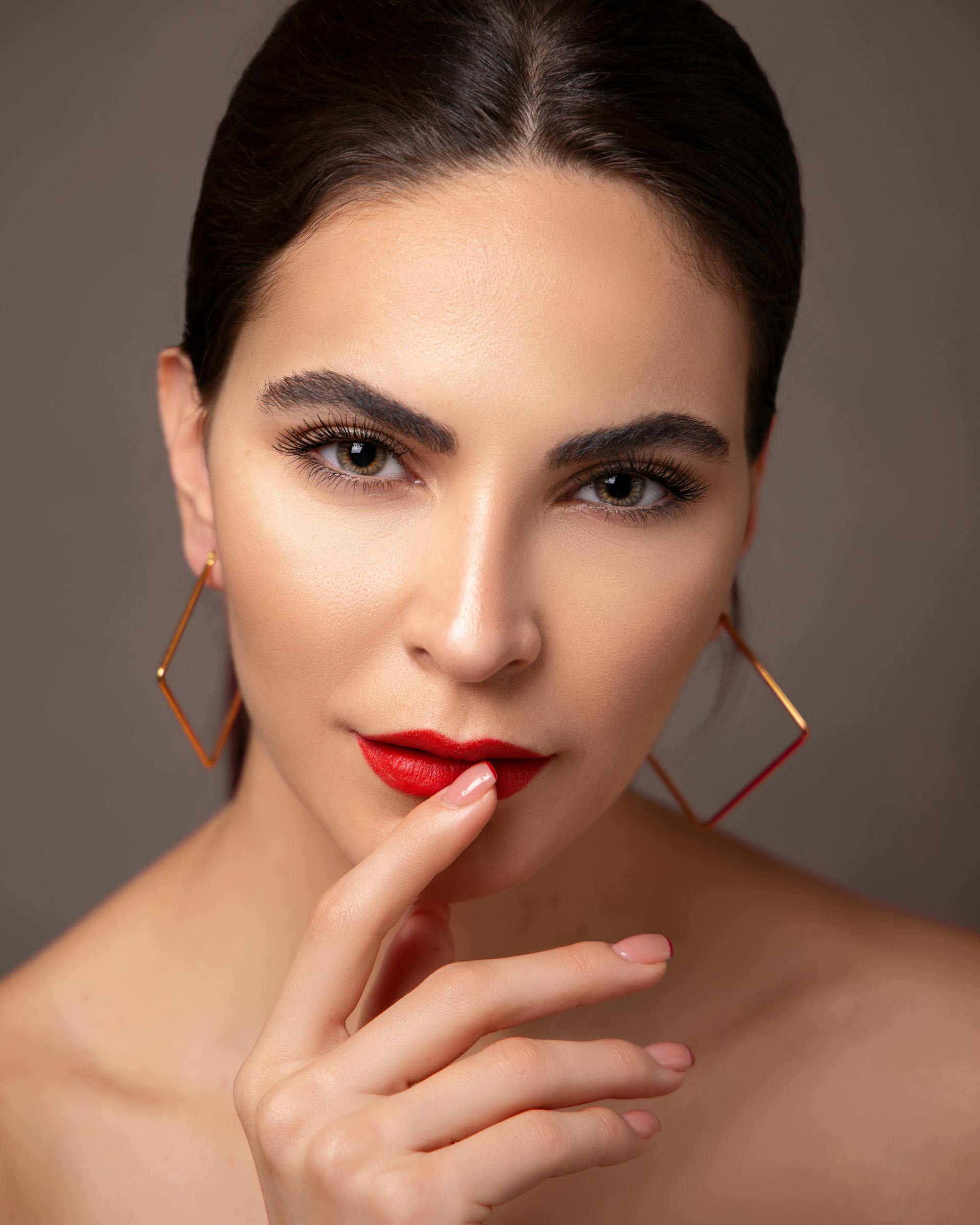 Une femme portant du rouge à lèvres rouge et des boucles d'oreilles | Source : Pexels