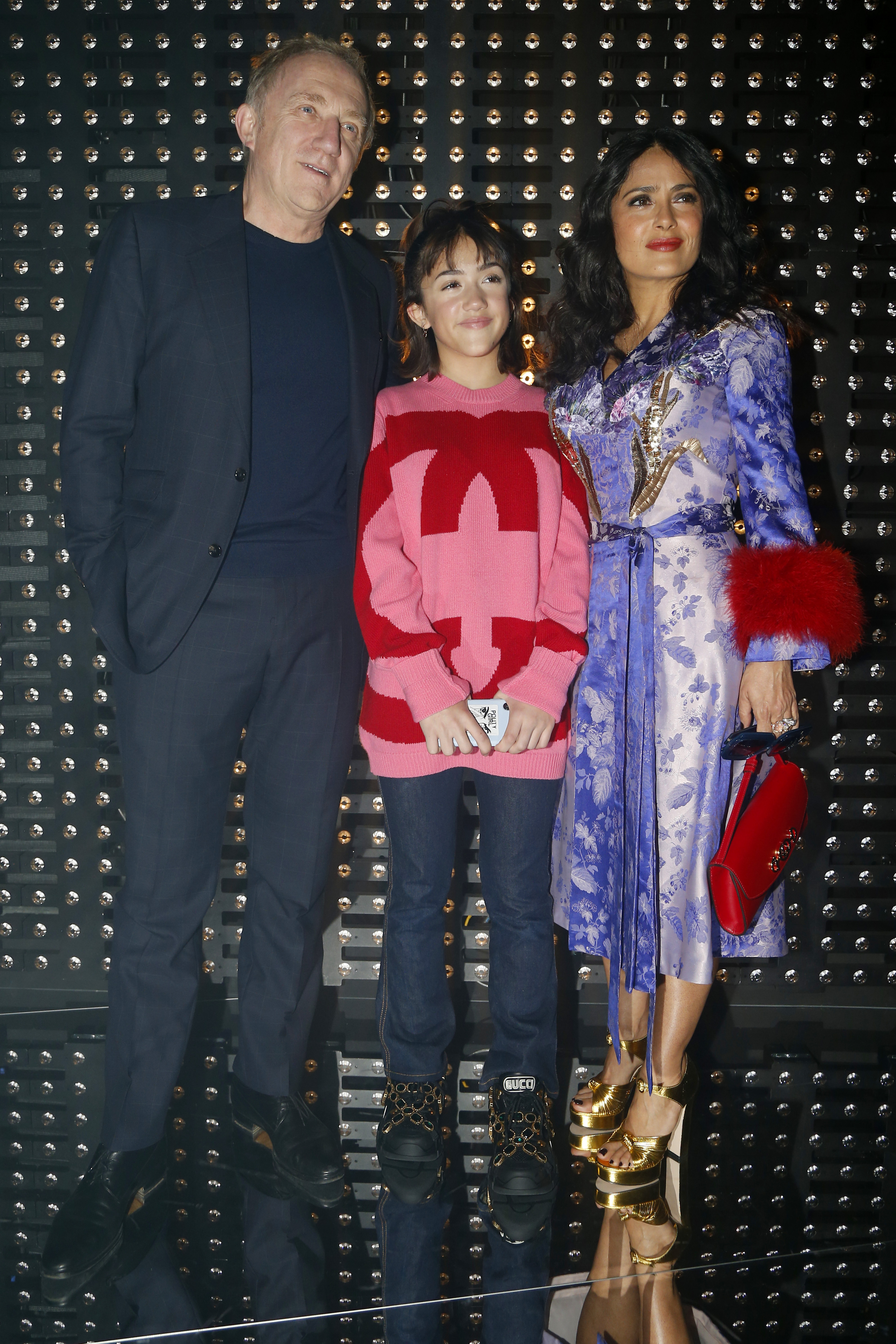 Au premier rang du défilé Gucci Automne/Hiver 2019 à Milan, Valentina Pinault rejoint ses parents, Salma Hayek et François-Henri Pinault. Salma éblouit dans une robe violette et dorée agrémentée d'accessoires remarquables, tandis que Valentina porte un pull oversize rouge et rose audacieux et un jean, se tenant avec assurance entre ses parents.