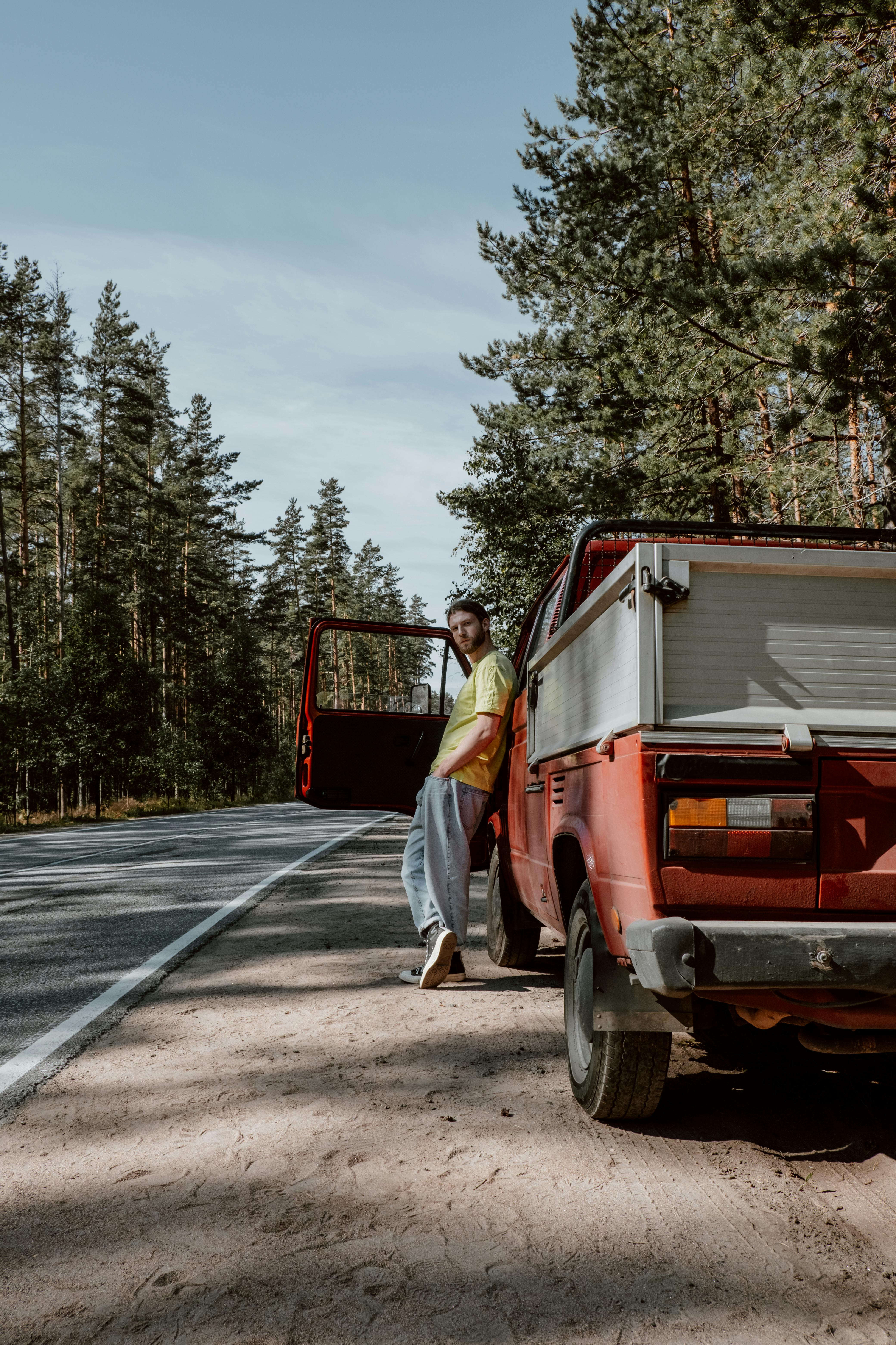 Un homme adossé à un pick-up rouge | Source : Pexels