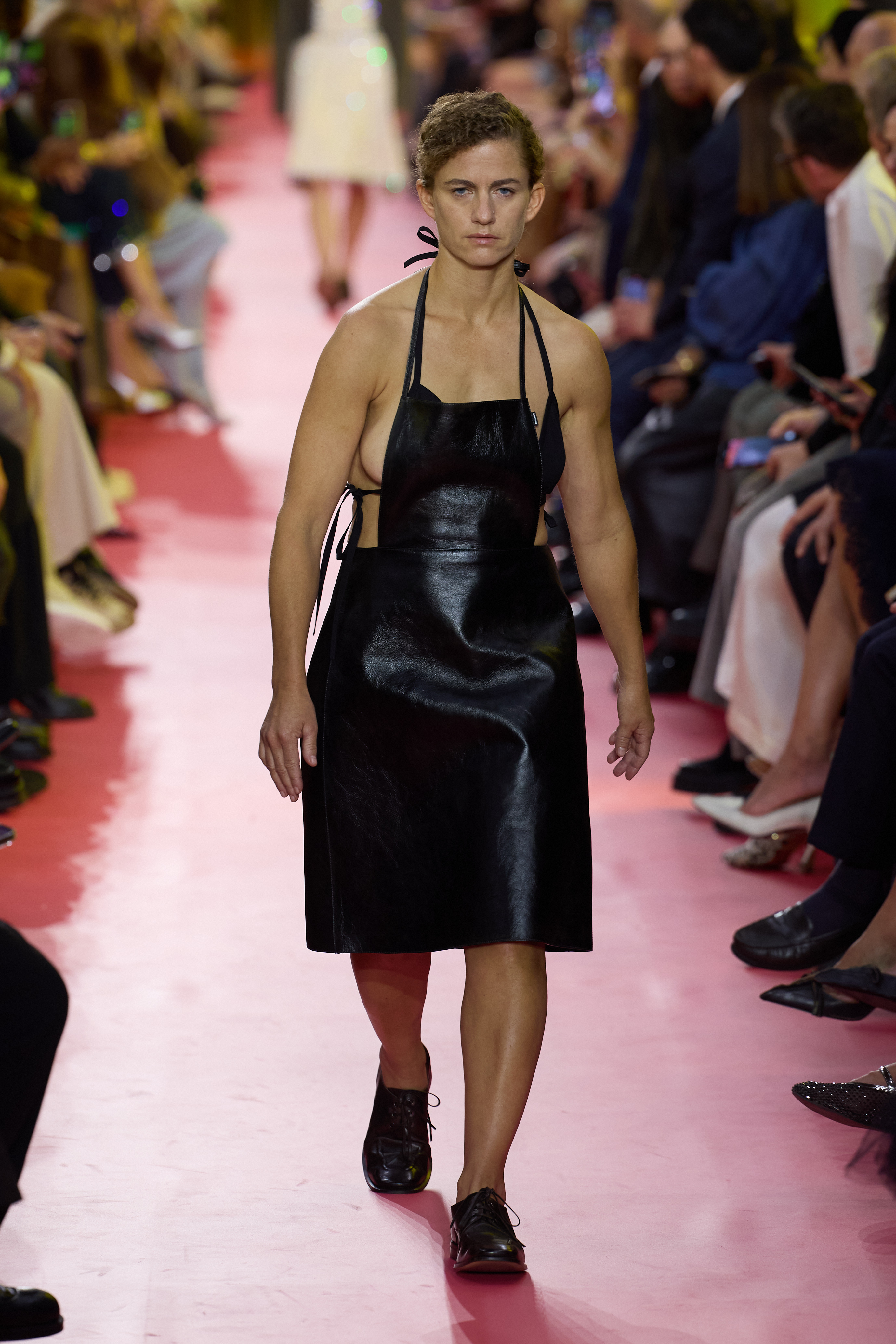 Une mannequin défile lors du défilé Miu Miu Femme Printemps/Été 2026 à la Fashion Week de Paris, en France. Le défilé était axé sur le tablier, comme on peut le voir sur le mannequin vêtu de cuir, une réinterprétation créative et saisissante de cette pièce classique.