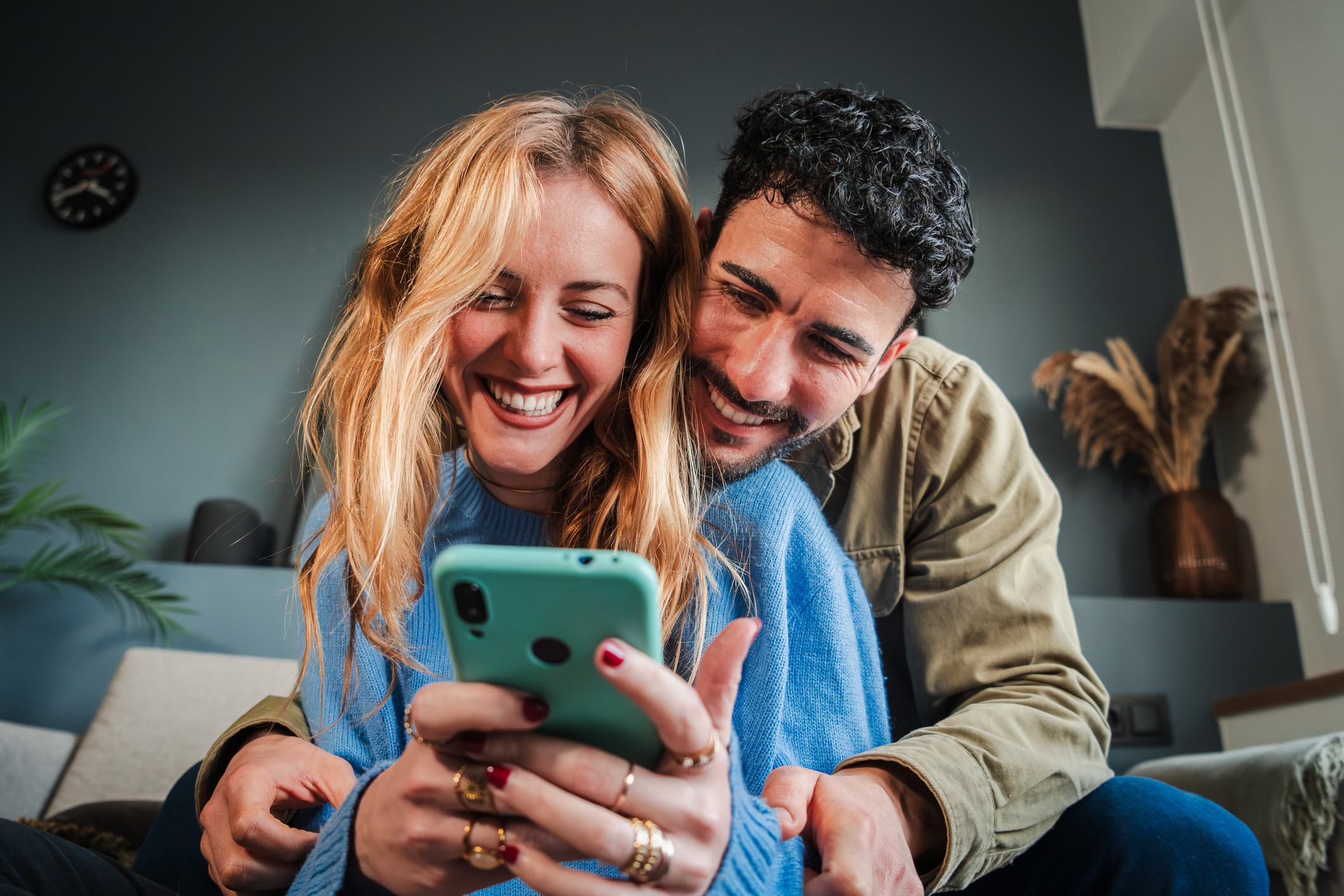 Jeune couple souriant utilisant un téléphone I Source : Getty Images