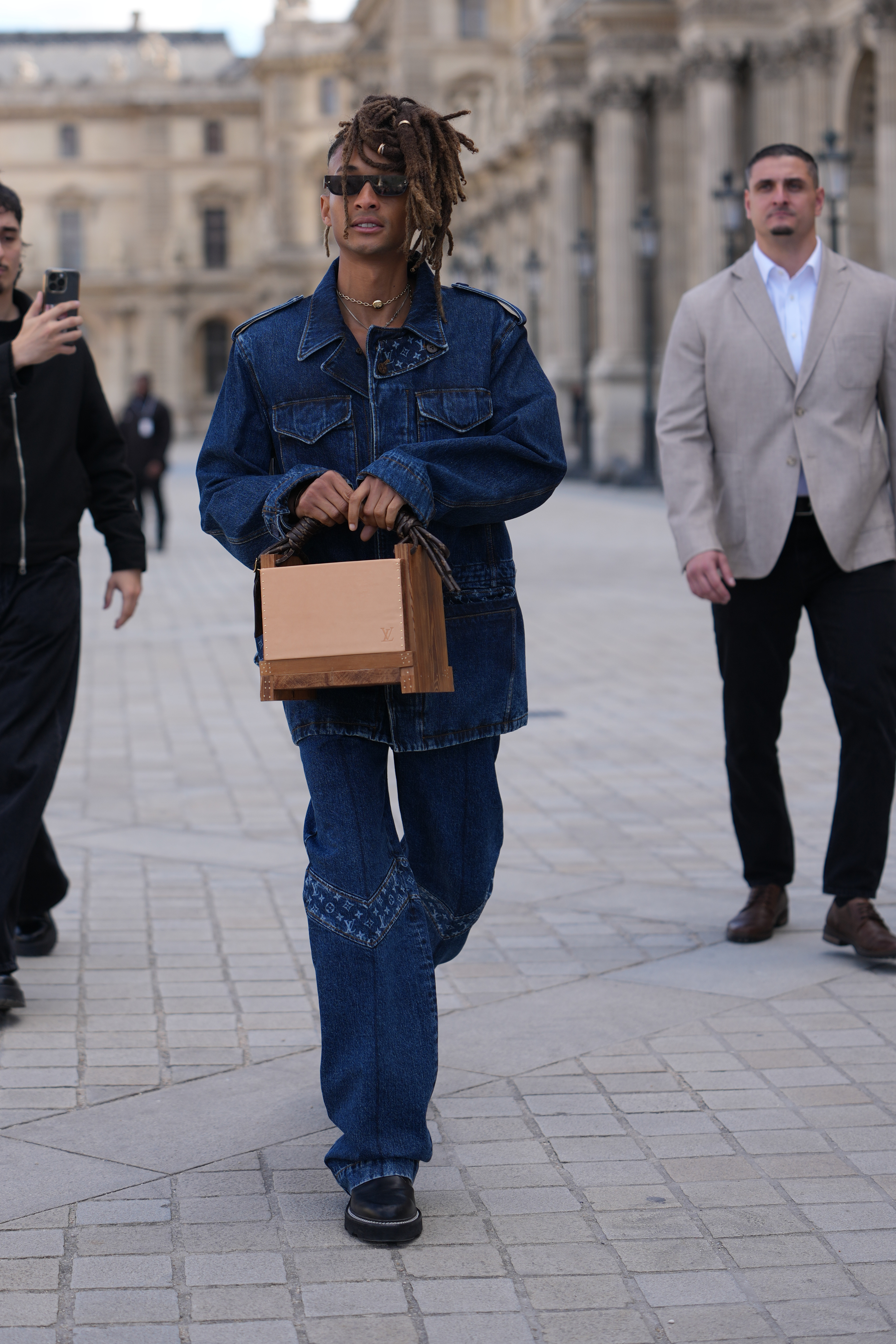 Jaden Smith aperçu devant la boutique Louis Vuitton lors de la Fashion Week Paris Femme Printemps/Été 2026 en France. Il portait une veste en denim indigo foncé, assortie à un jean droit ample. Il a complété son look avec une pochette en bois et des chaussures à semelles compensées en cuir noir à talons bas.