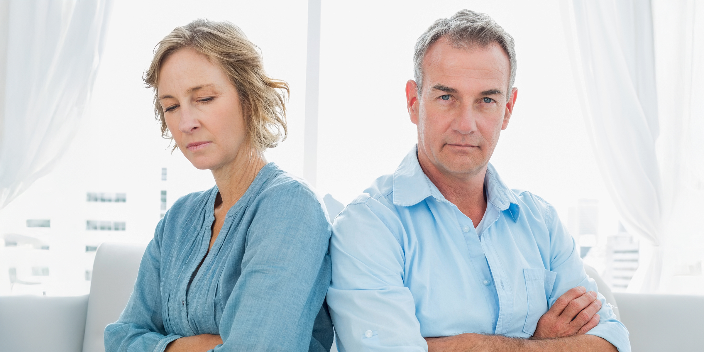 Un couple d'âge moyen tendu, assis les bras croisés | Source : Shutterstock