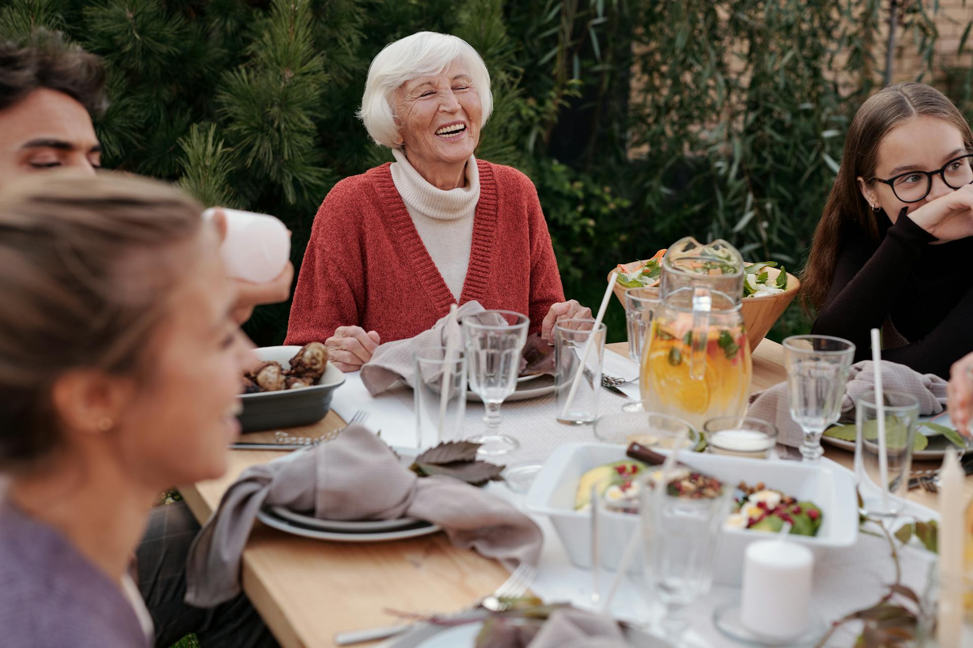 Une femme âgée rit en dînant avec sa famille dans l'arrière-cour | Source : Pexels